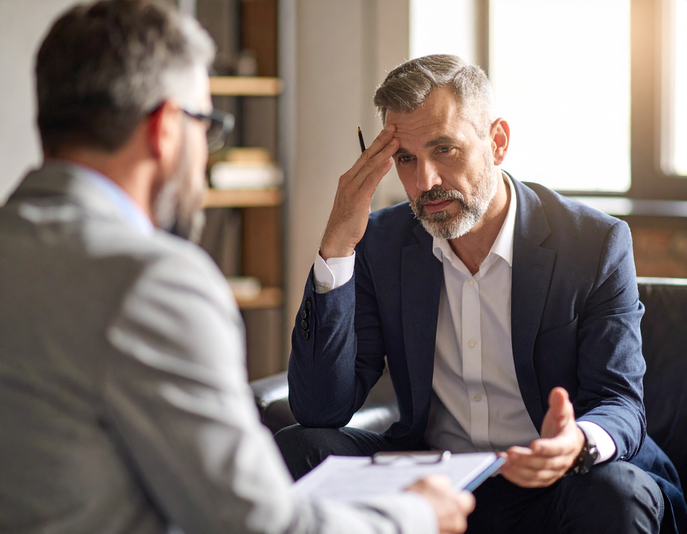 A tired and sad man, seeking help with a crisis from a psychiatrist.