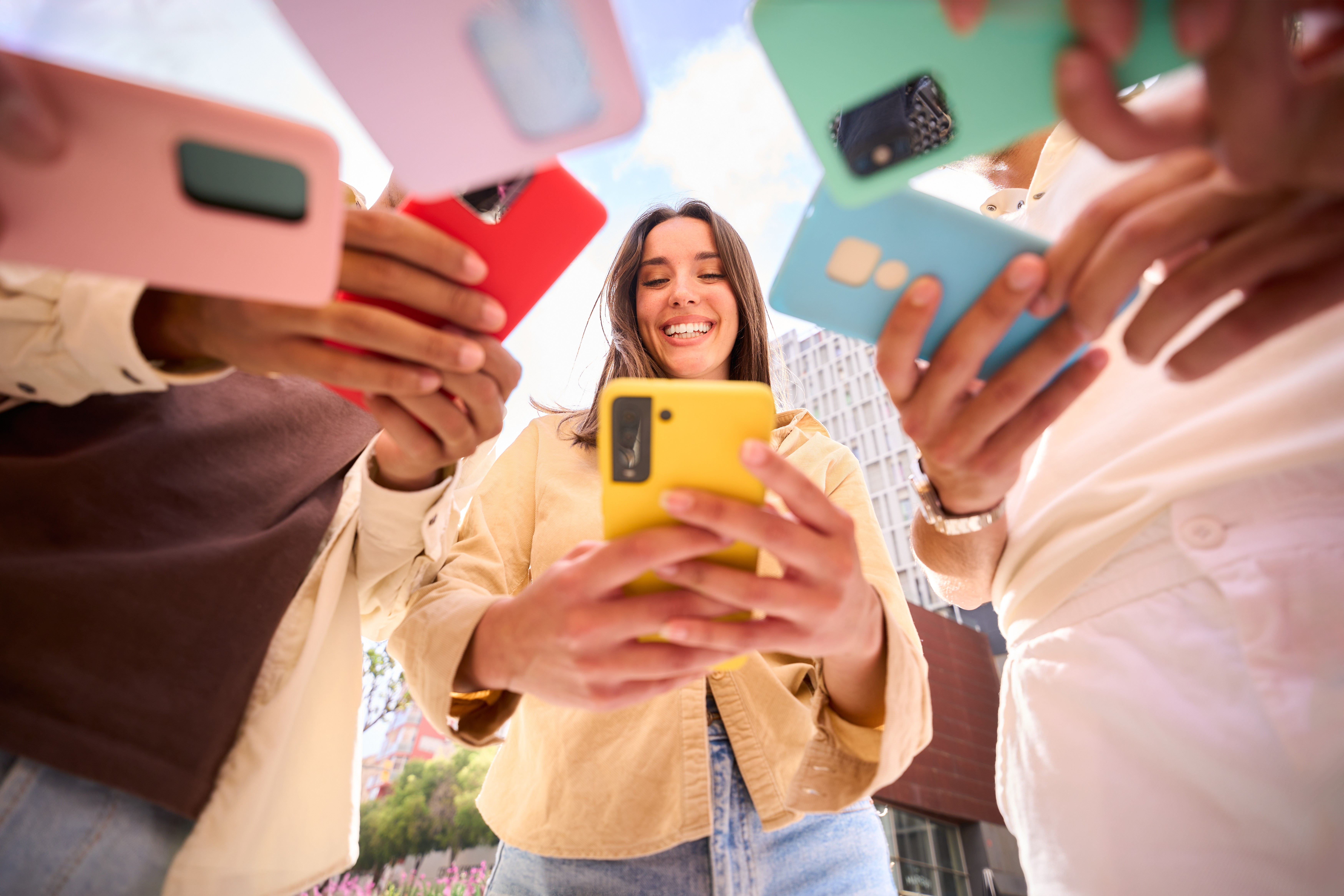 Celulares coloridos juntos e uma mulher feliz por terem conquistado o celular dos sonhos.