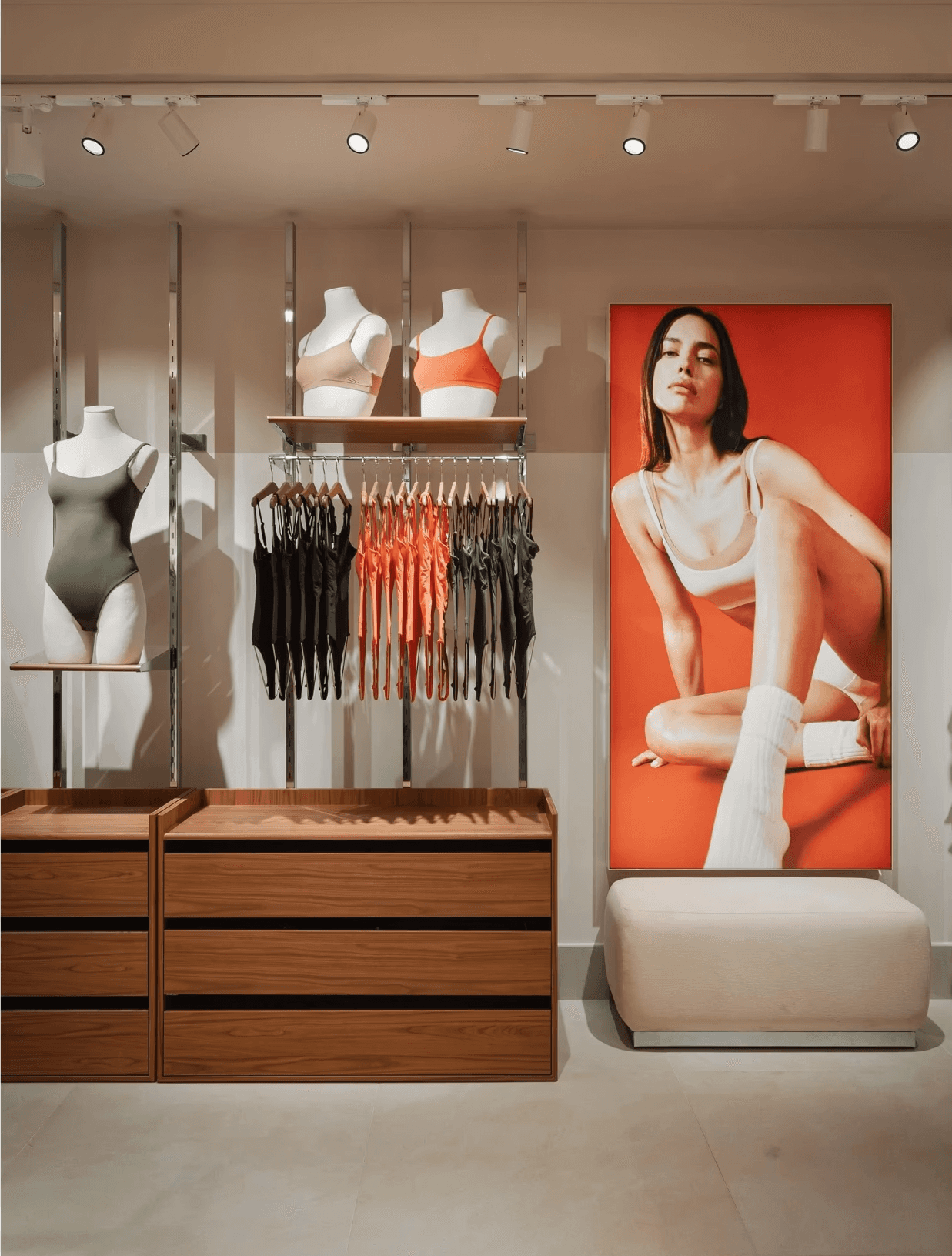 Maillots de bain colorés accrochés, mannequins bustes, affiche modèle en sous-vêtements sur fond orange