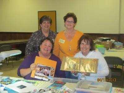 Four scrapbookers showing off their finished albums and pages