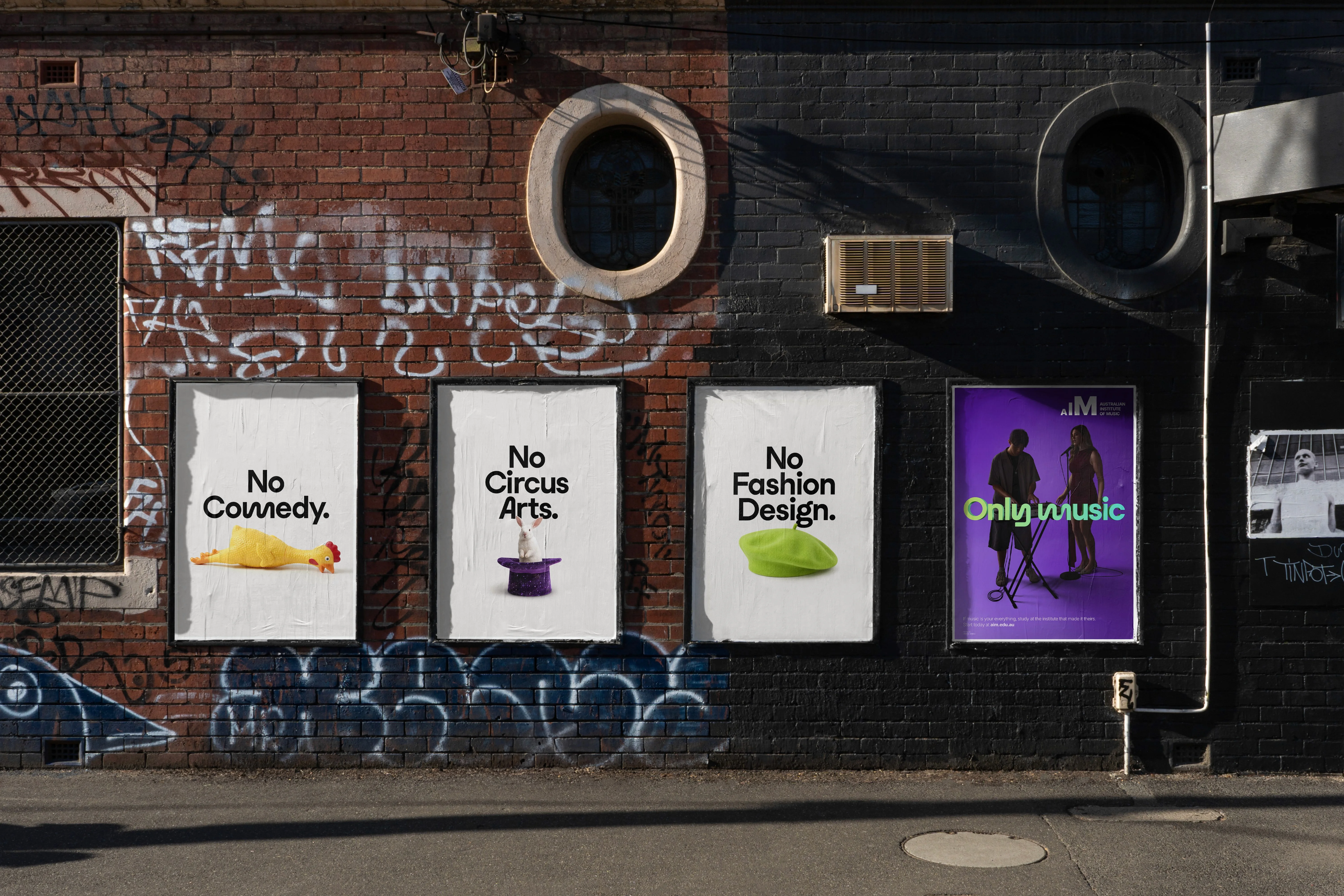 Only Music posters on a graffitied brick wall: 'No Comedy.', 'No Circus Arts.', 'No Fashion Design.' and an AIM poster