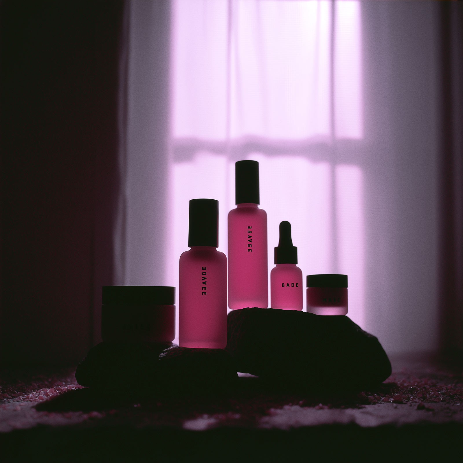 Pink cosmetic bottles on shelf in dim lighting
