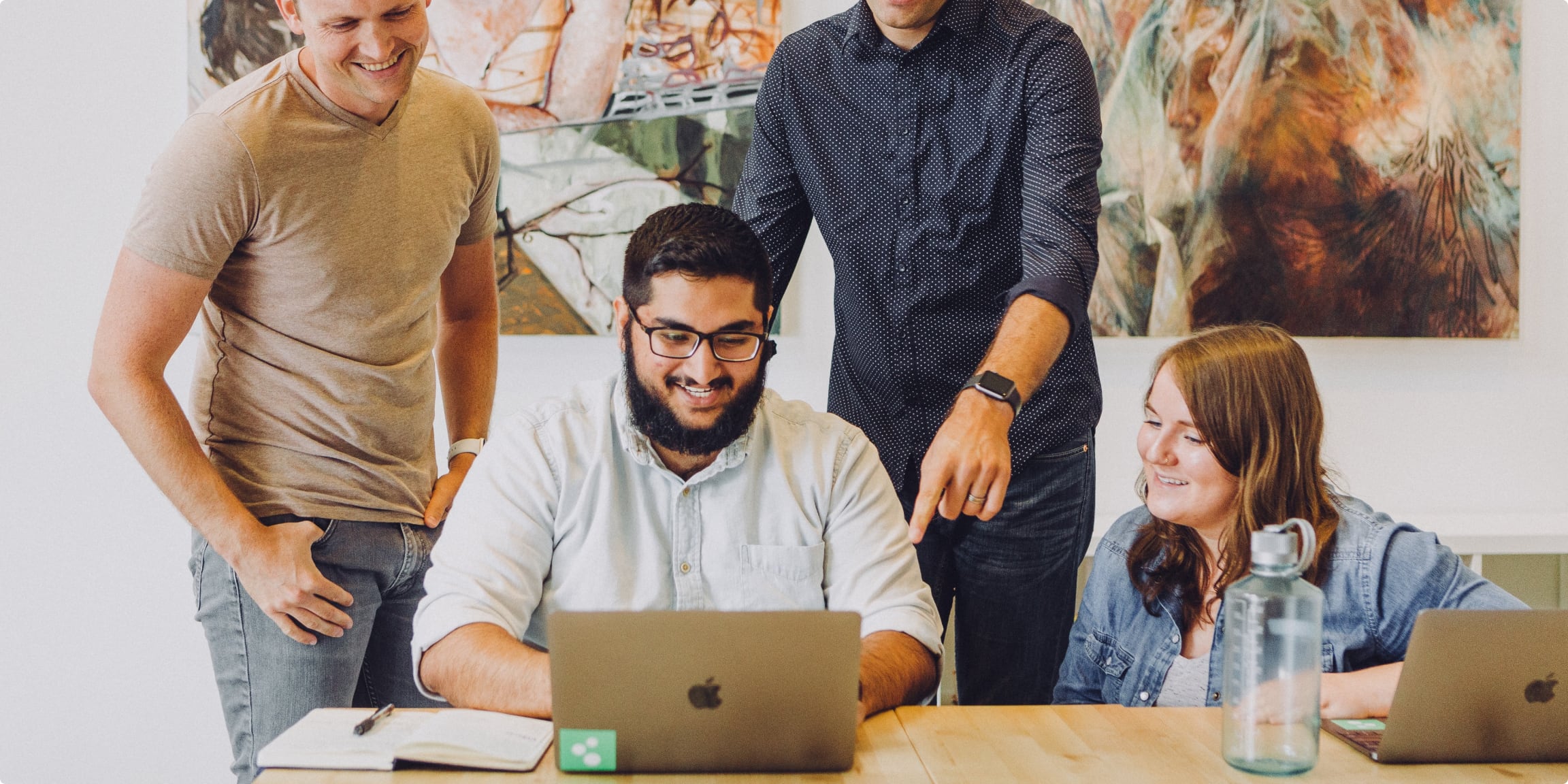 Decorative image of a work group smiling while looking at a computer screen.