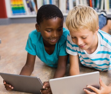 meninos lendo em tablet na biblioteca escolar