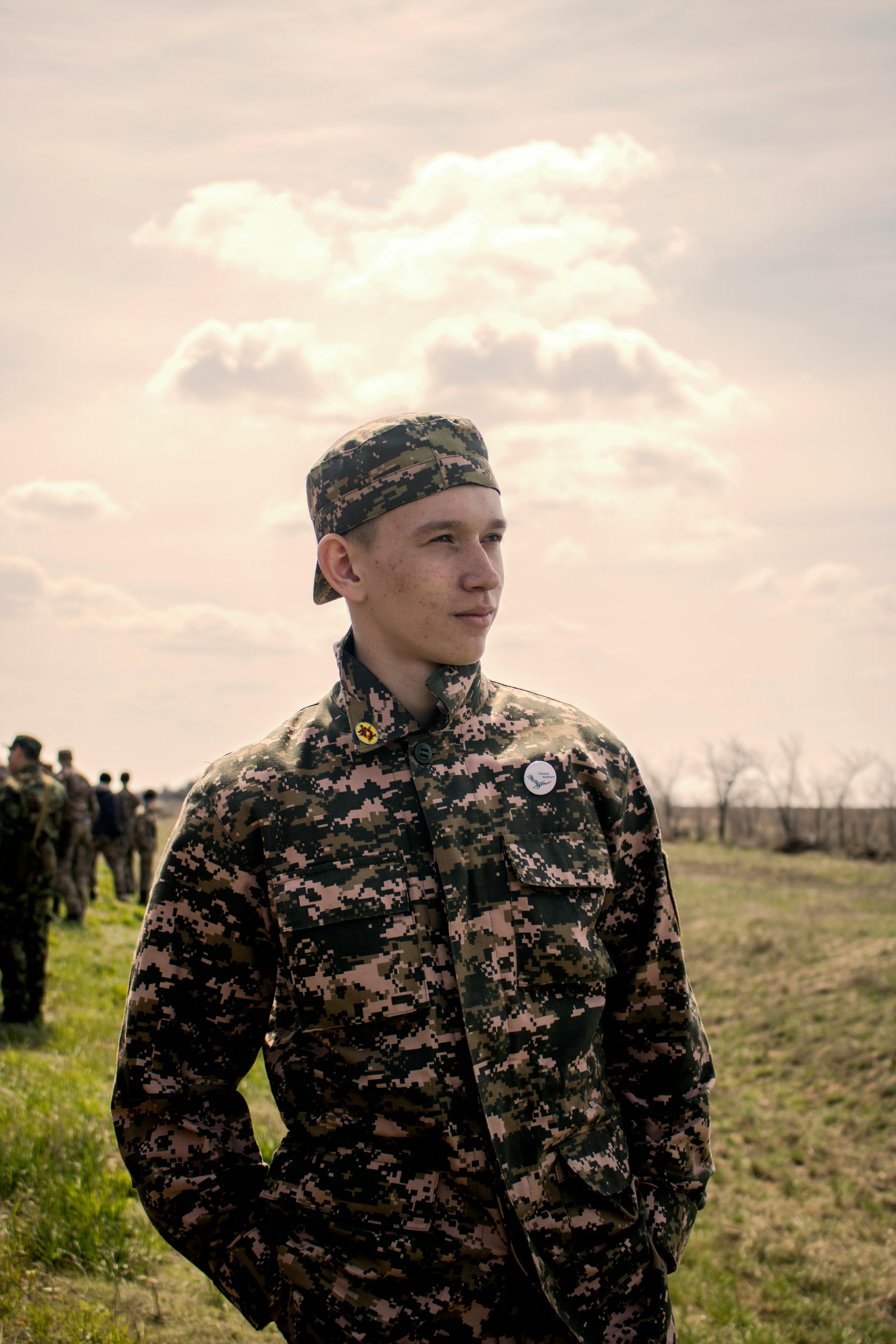 A young soldier gazes into the distance as the sun sets in the background.