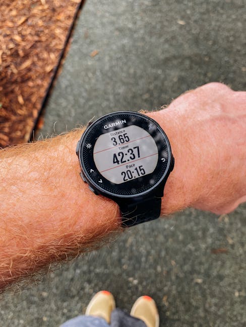 Close-up of a smartwatch showing running distance, time, and pace on a wrist outdoors.