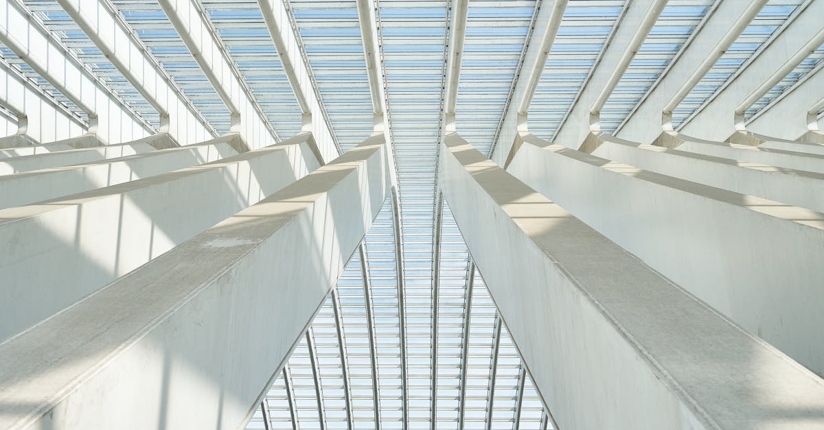 A striking upward view of a modern ceiling structure featuring geometric beams and glass panels.