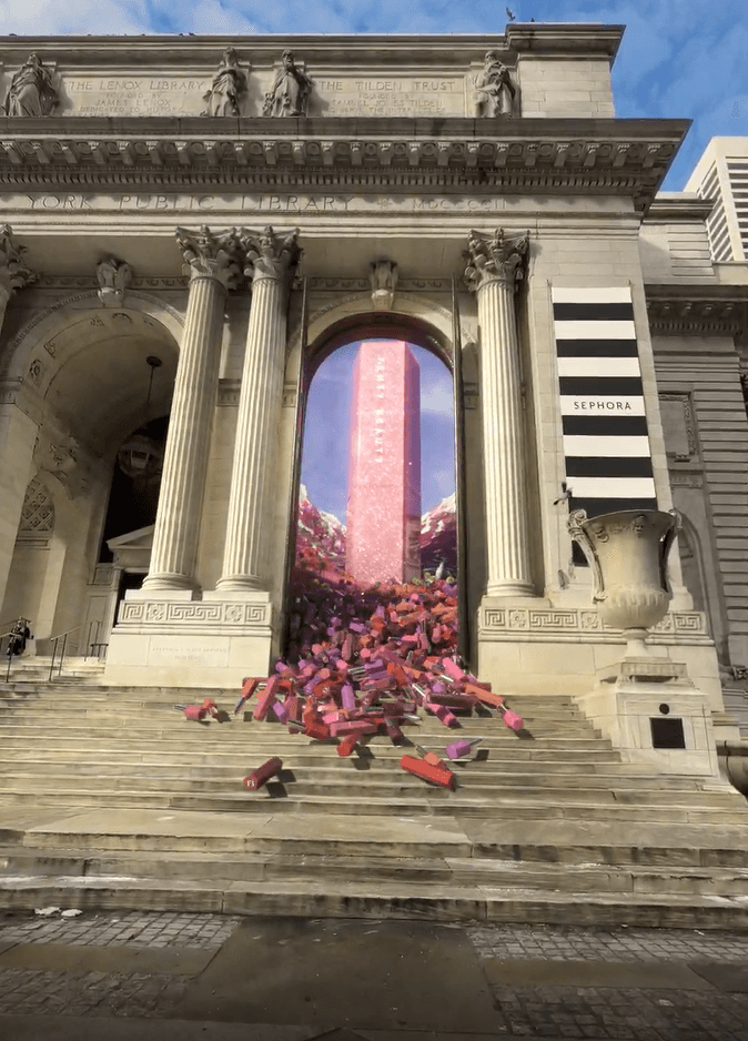 A mixed-reality shot features a giant Fenty Beauty lip gloss tower inside the archway with lipsticks spilling down the stairs.