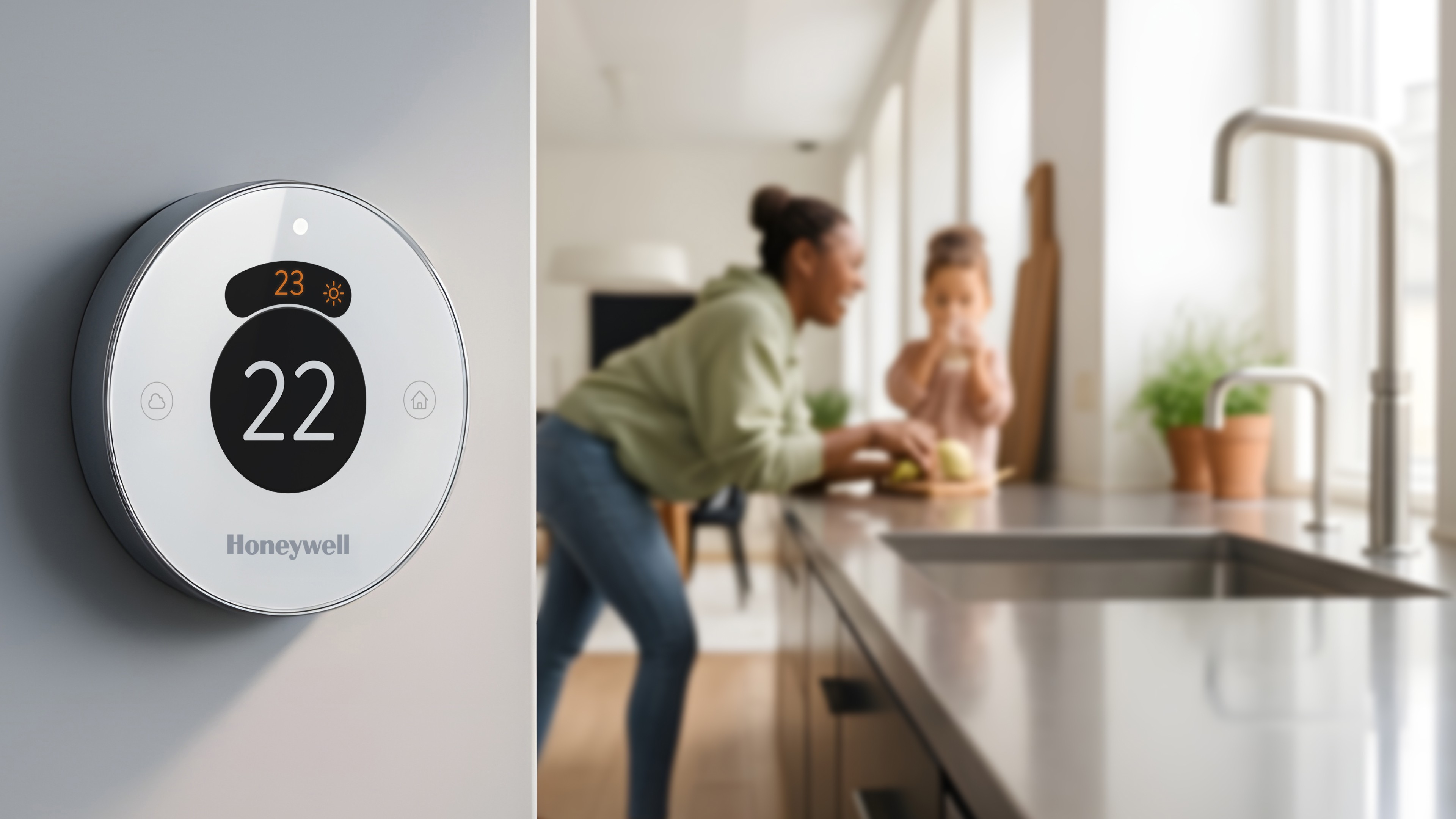 Smart Honeywell thermostat with blurred background of mother and daughter in modern kitchen