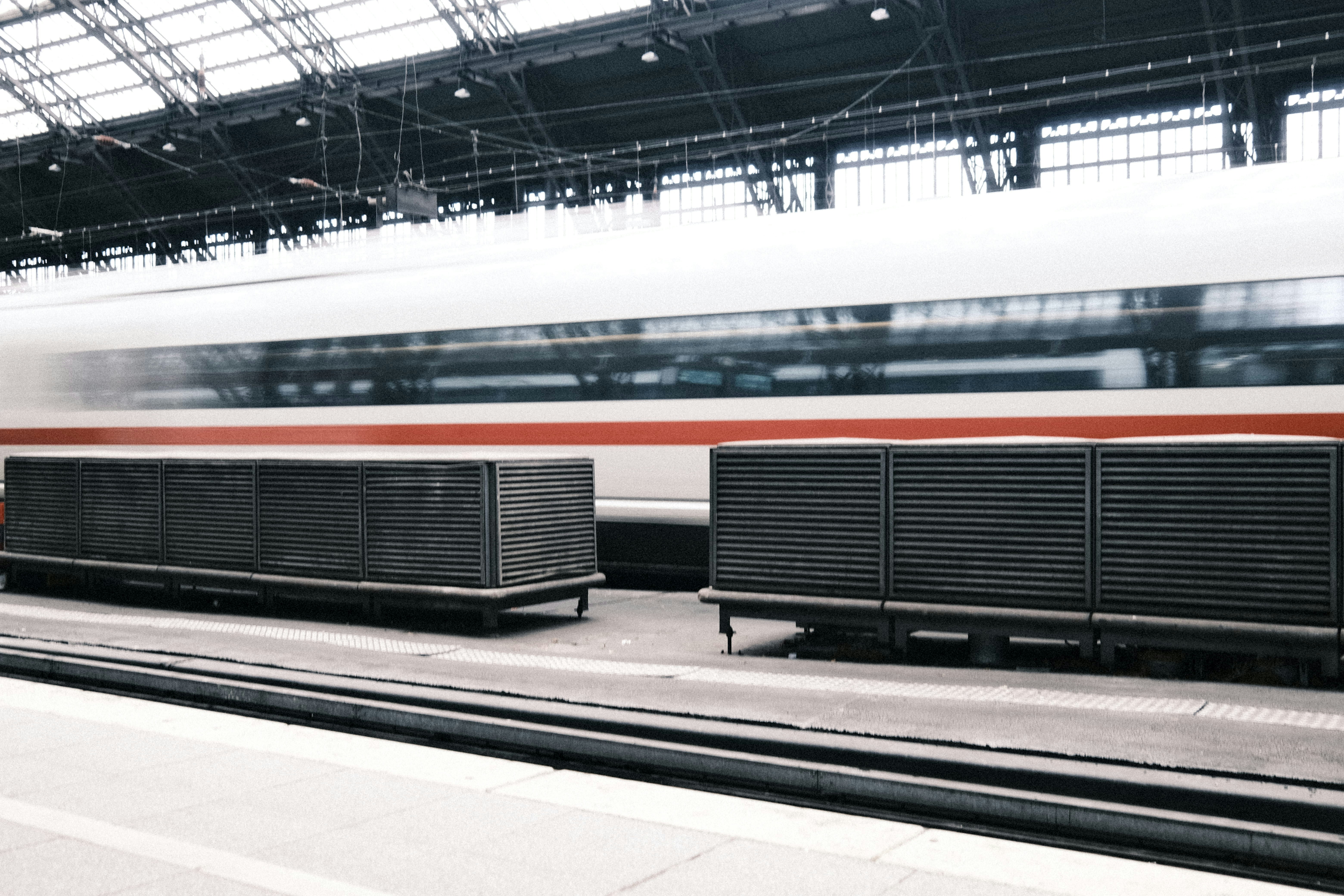 a train traveling past a train station next to a loading platform