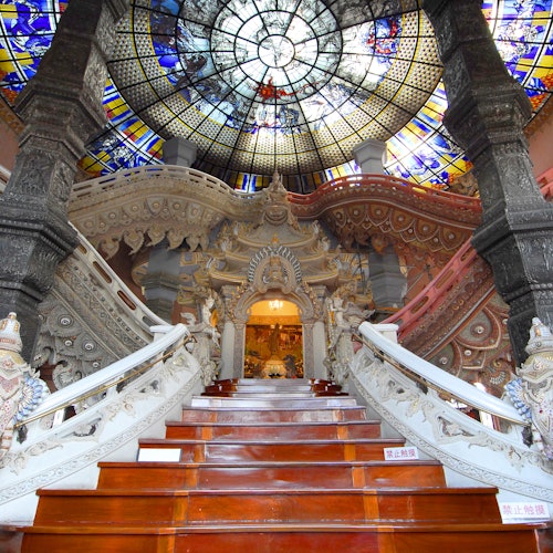 华丽的室内装饰，宏伟而精美装饰的楼梯通向一个色彩鲜艳的彩色玻璃圆顶，特色是复杂的雕刻和柱子。