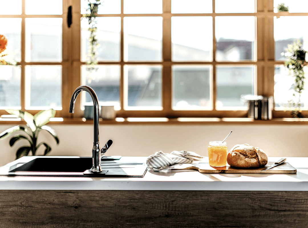 A light airy kitchen sink with a concrete countertop. A window behind has wood trim.