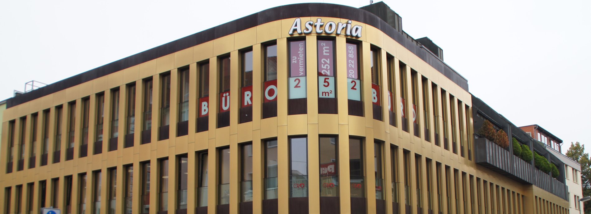 Astoria Bürogebäude mit goldener Fassade, Fenster und Schriftzug
