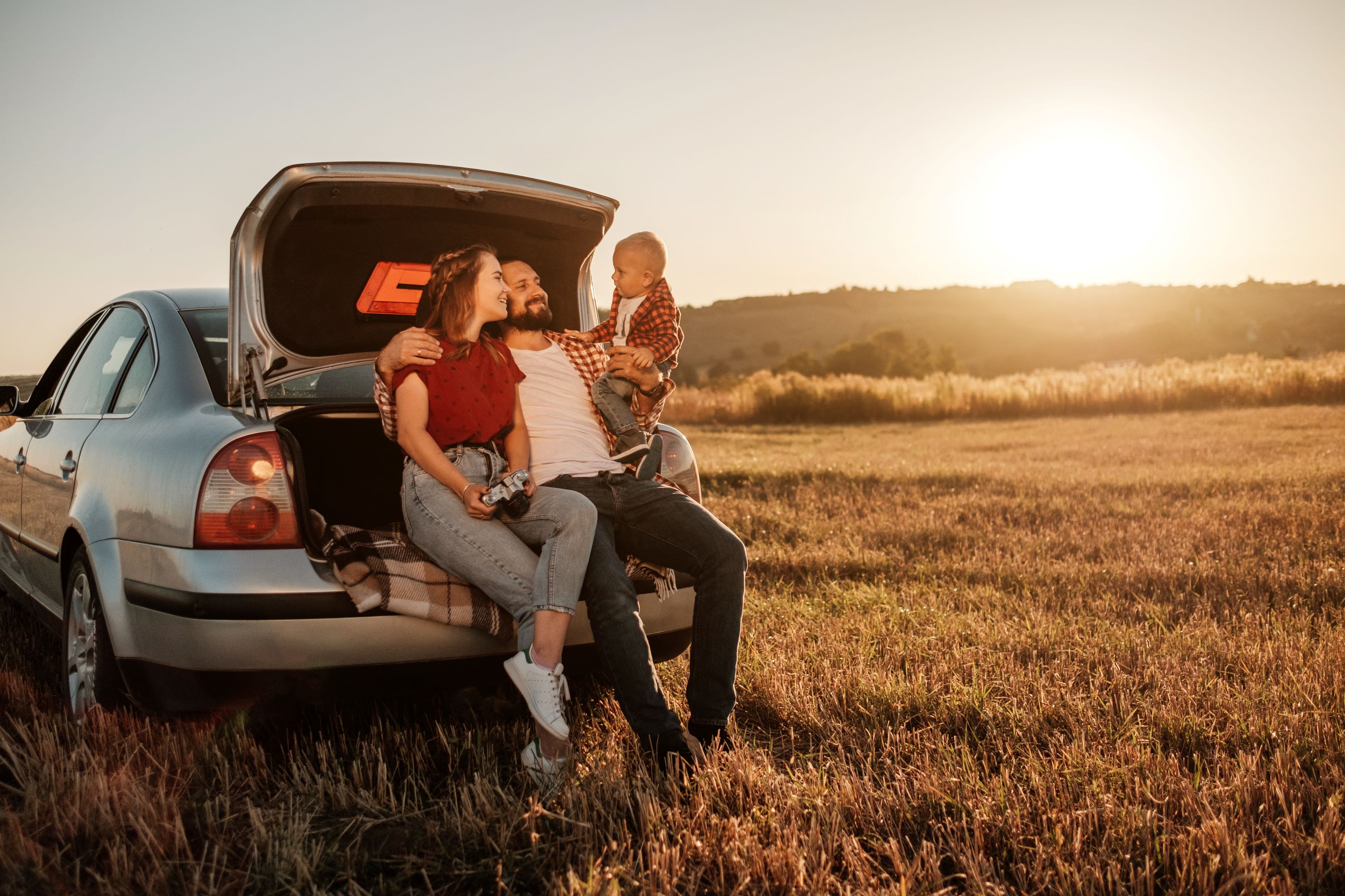 Happy family with car in Wichita, KS enjoying affordable auto insurance