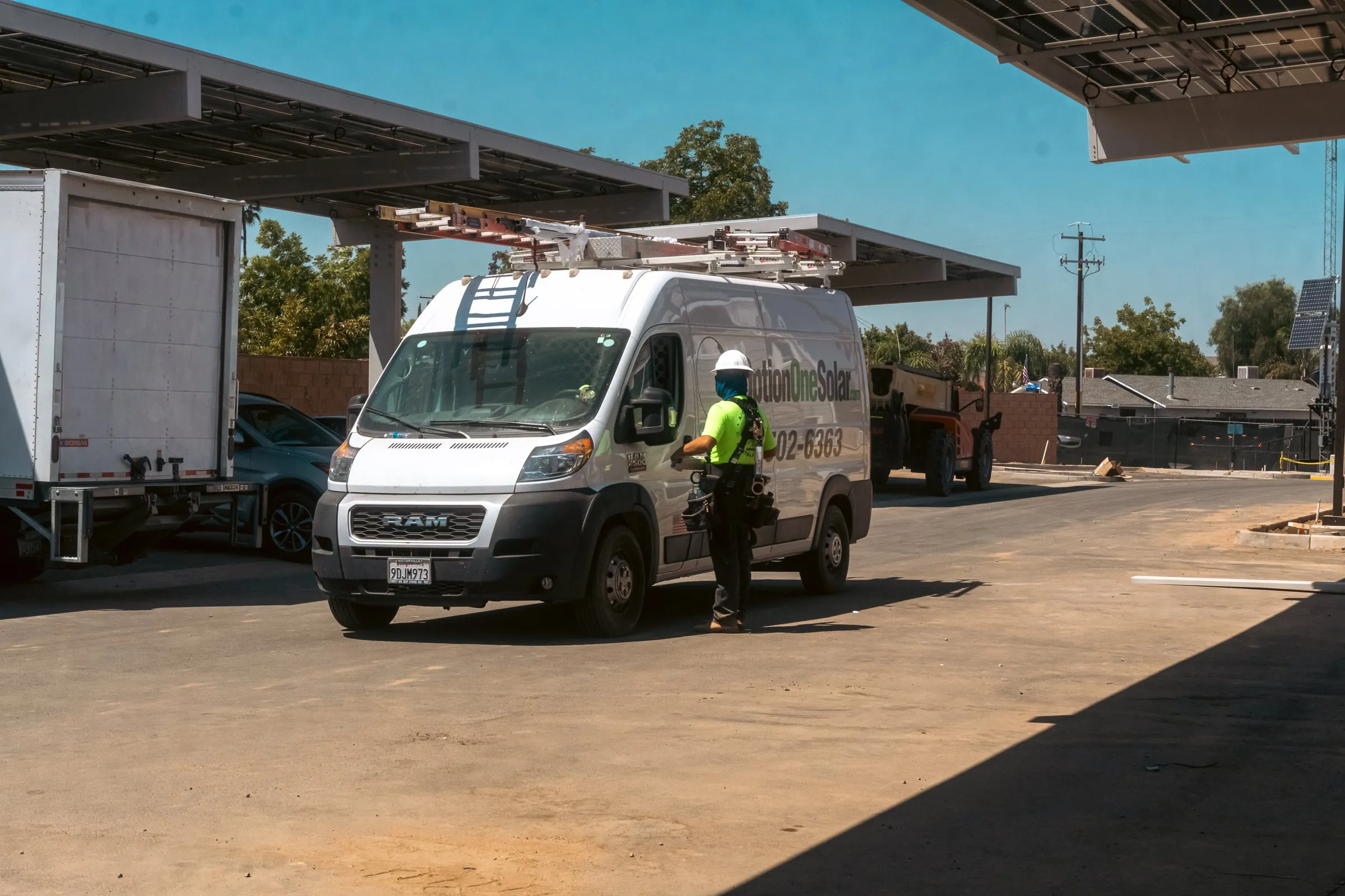 An Option One Solar service van parked beside a solar carport under construction