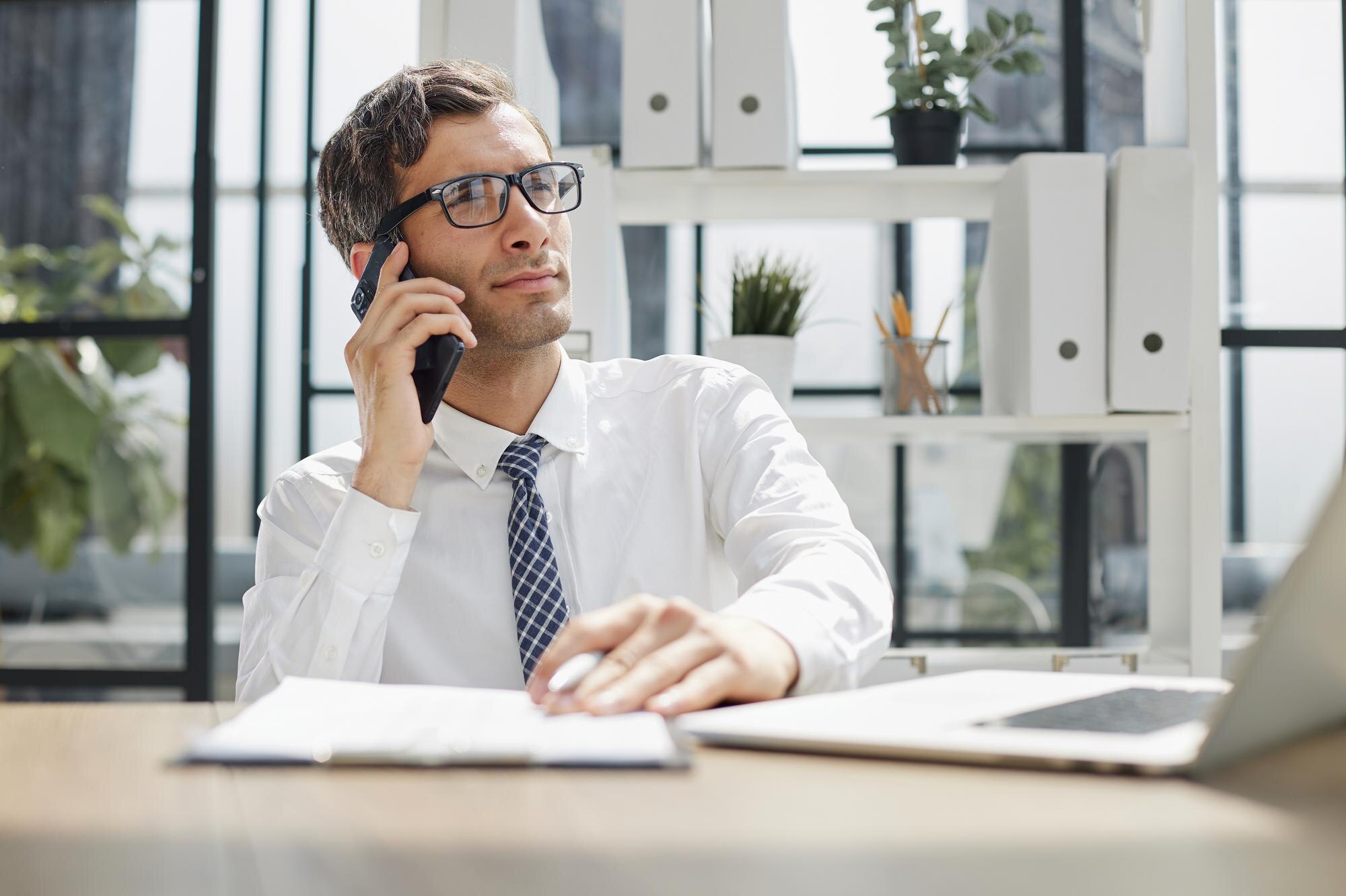 Accountant aan bureau met telefoon, symboliseert AI-telefoniste voor accountantskantoor