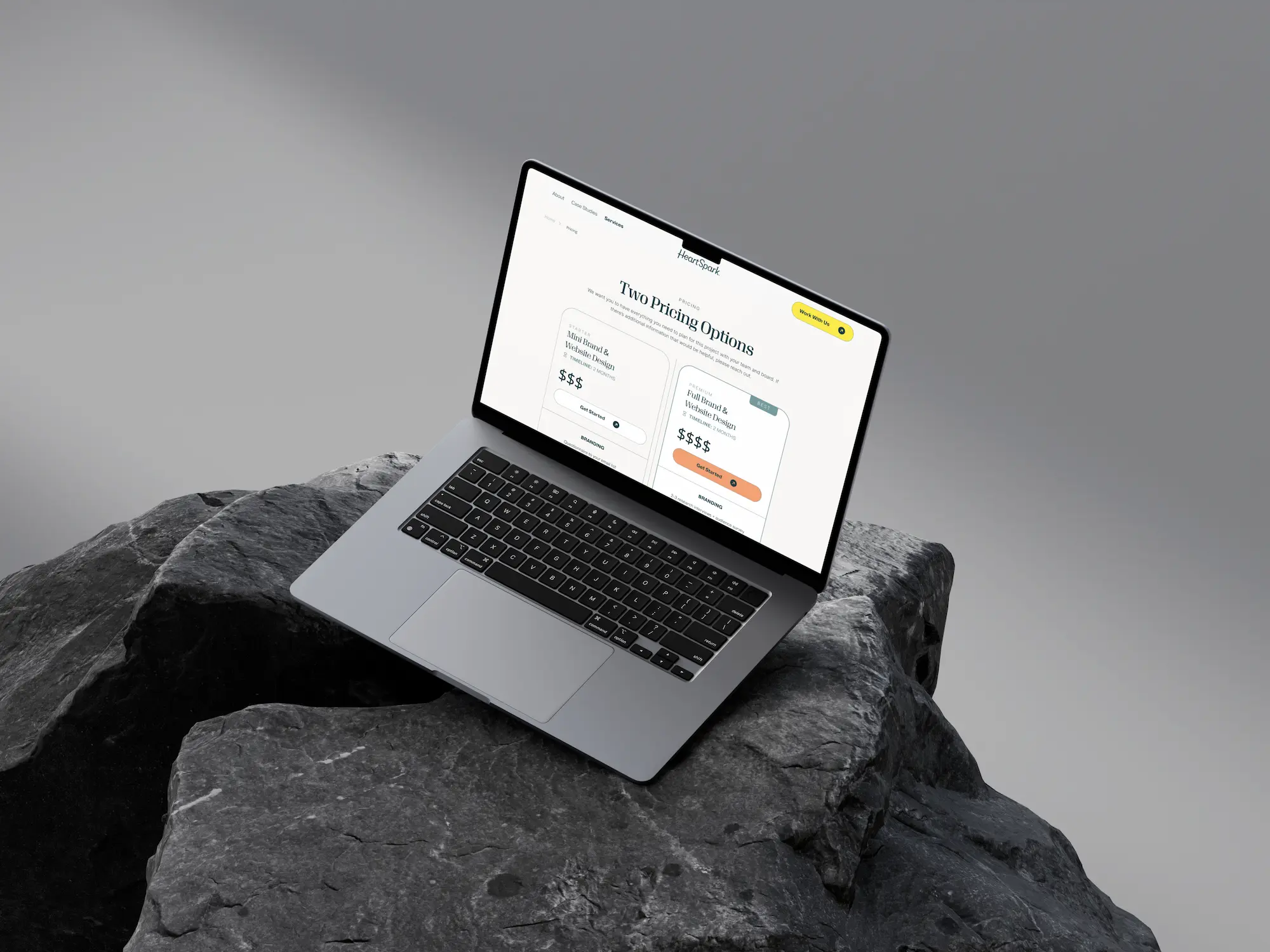 A laptop on a dark rocky surface displaying a website with a clean, modern design.