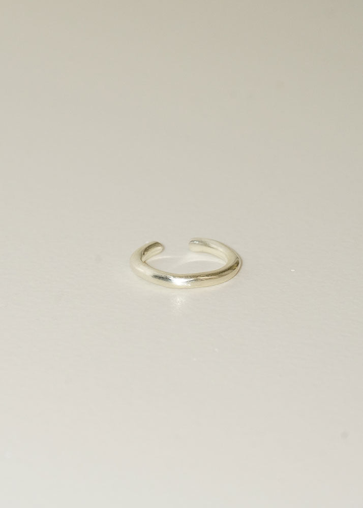 Silver open ring on a light beige background