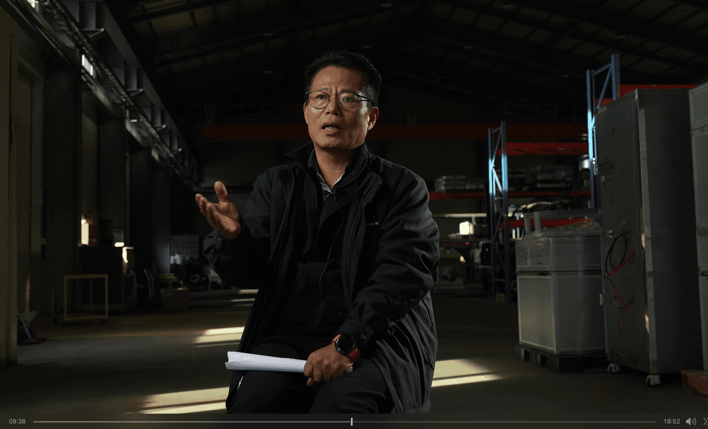 Modern staircase with wooden steps and black railing, decorated with hanging gold lights. Bright white walls feature abstract art, creating a sleek, airy ambiance.