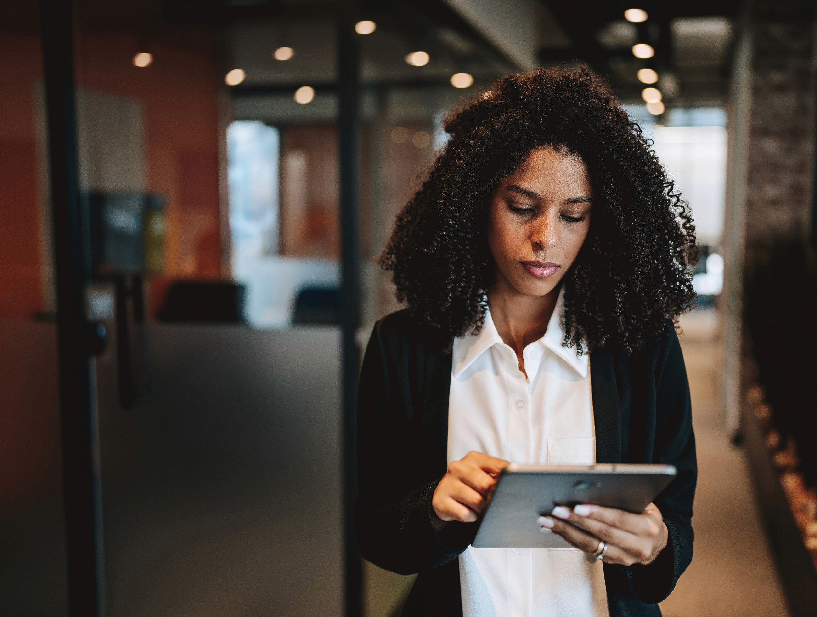 Smiling businesswoman shaking hands with someone across a table in an office setting.