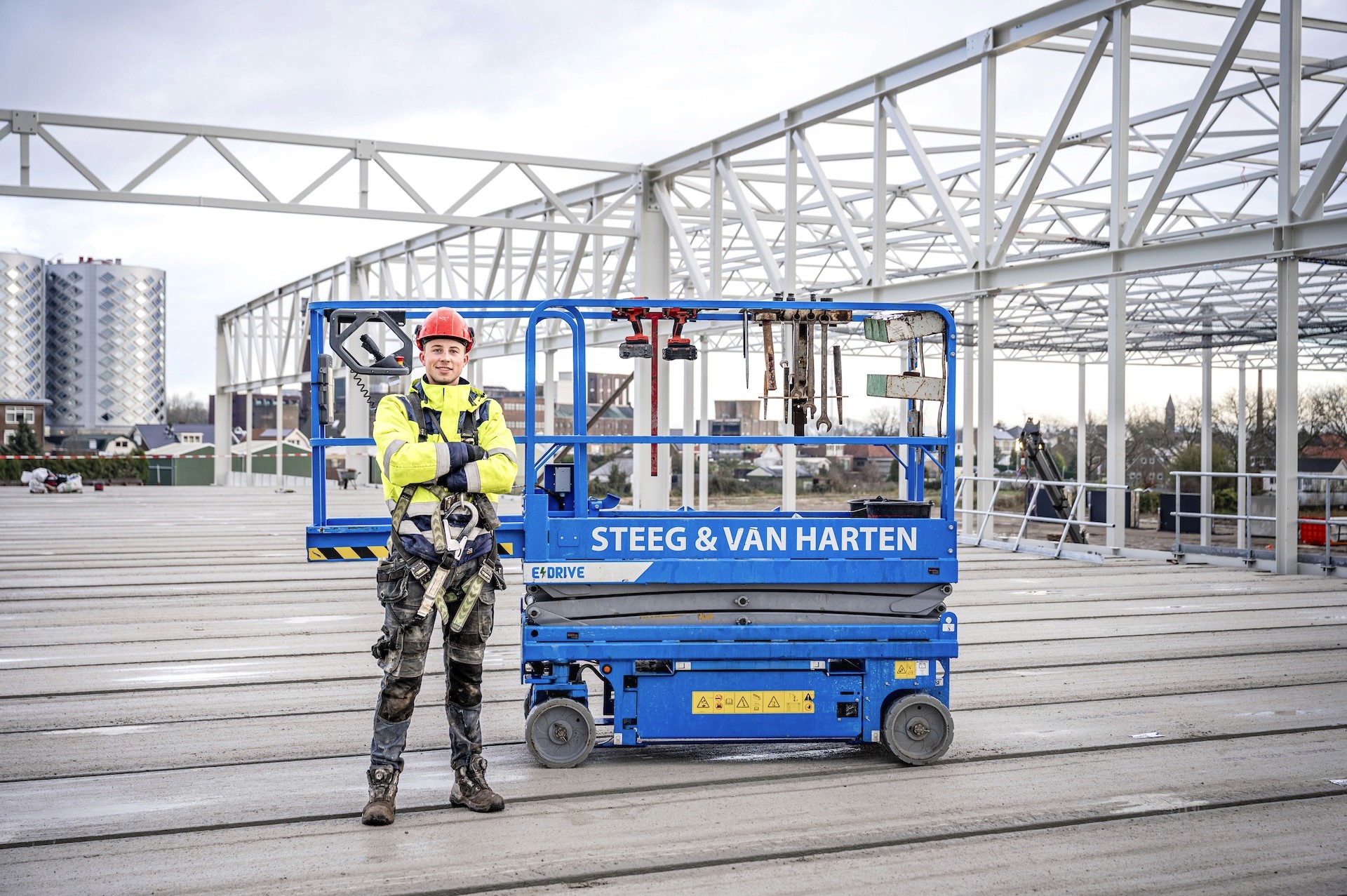 Portretfoto van medewerker Steeg en van Harten op de klus, naast blauwe hoogwerker