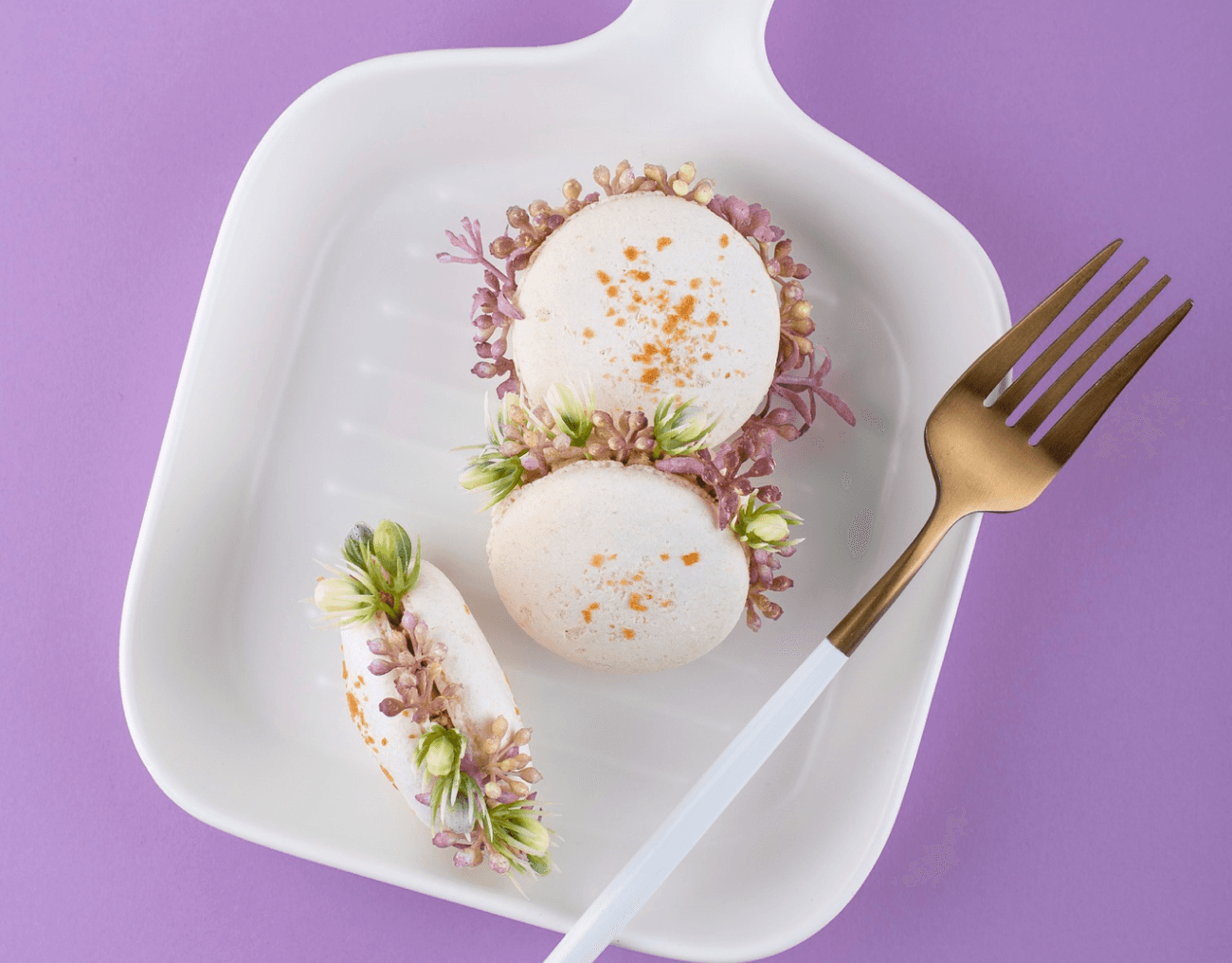 White macarons decorated with tiny purple and green flowers