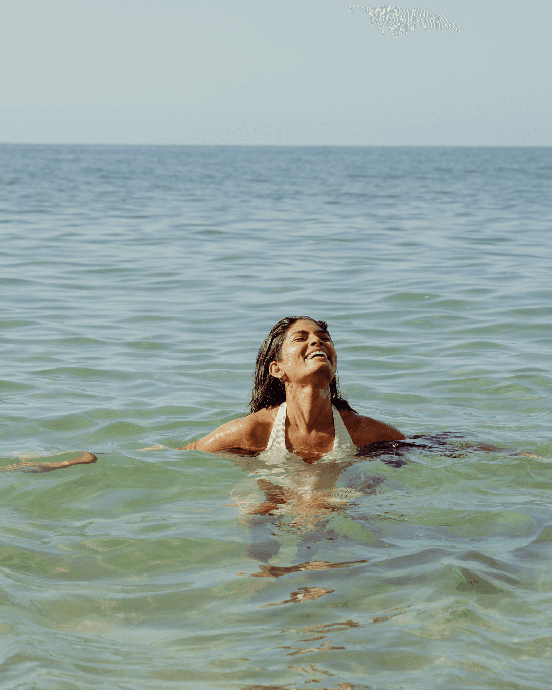 Woman in a bikini laughing in the ocean