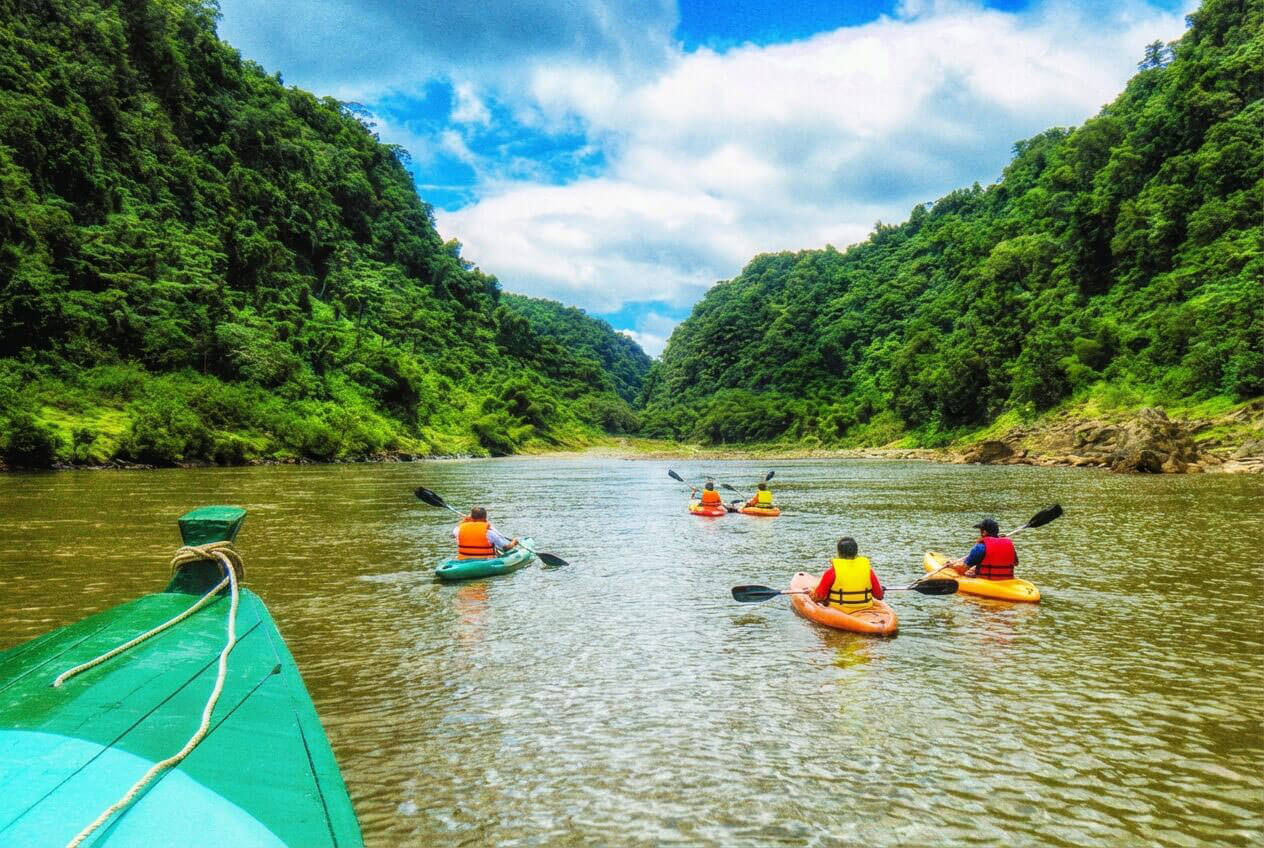 Kayaking in the waters of Fiji - group heading down river in kayaks