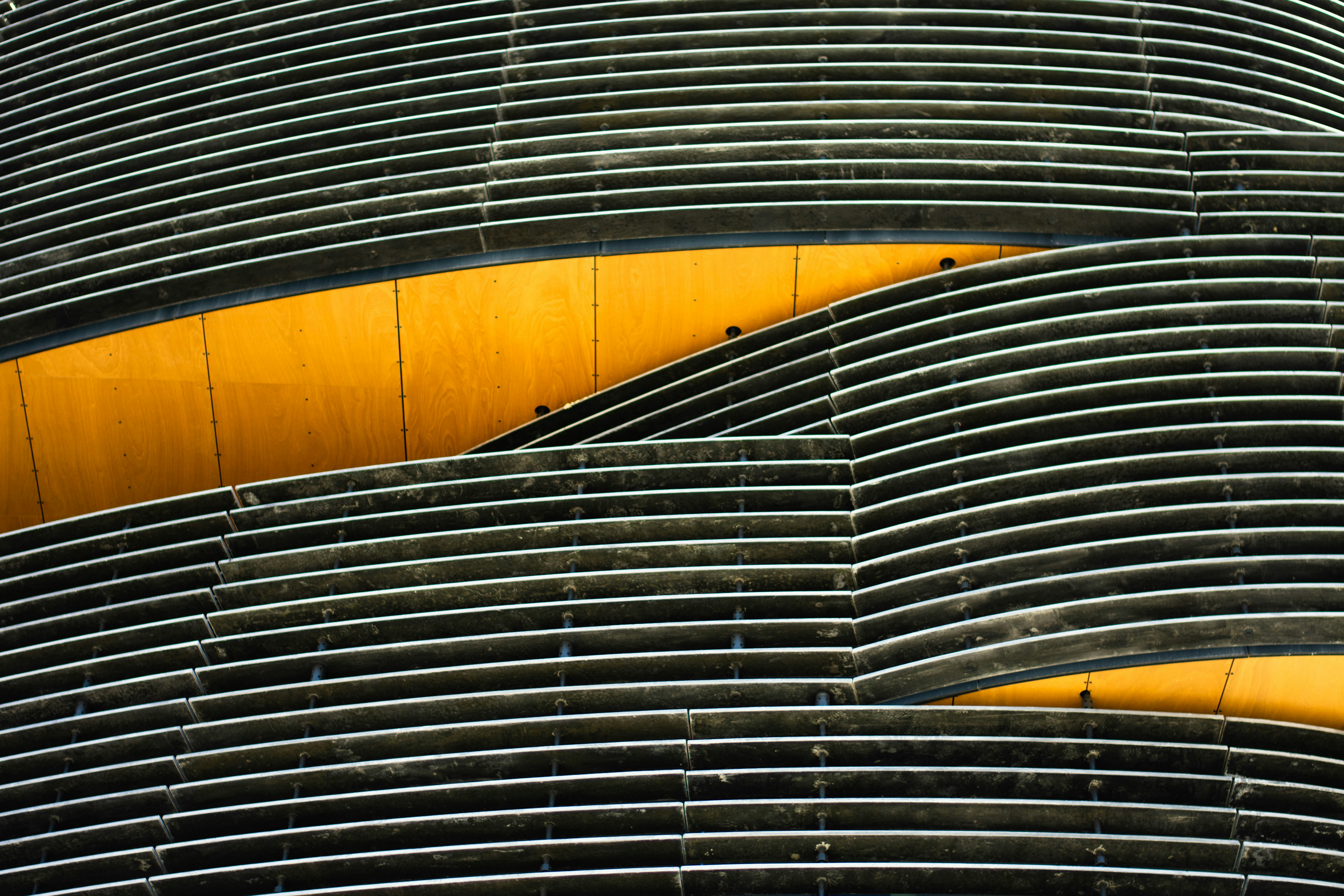 Curved gray louvers against yellow wood paneling.