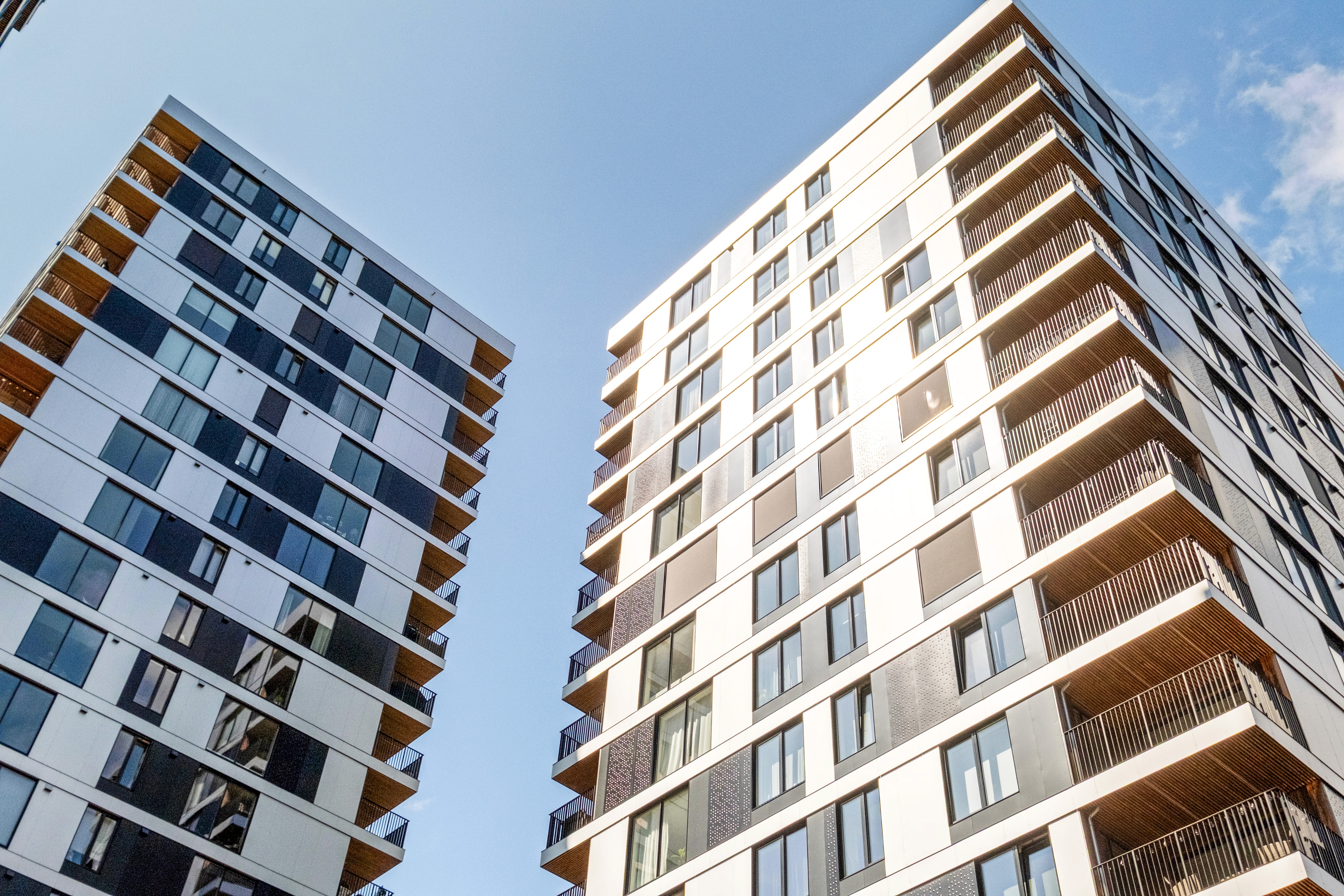 Moderne høyblokk sett fra gateplan mot blå himmel