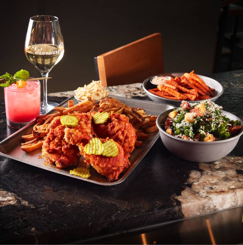 Chicken wings, salad, fries with a glass of wine and a cocktail