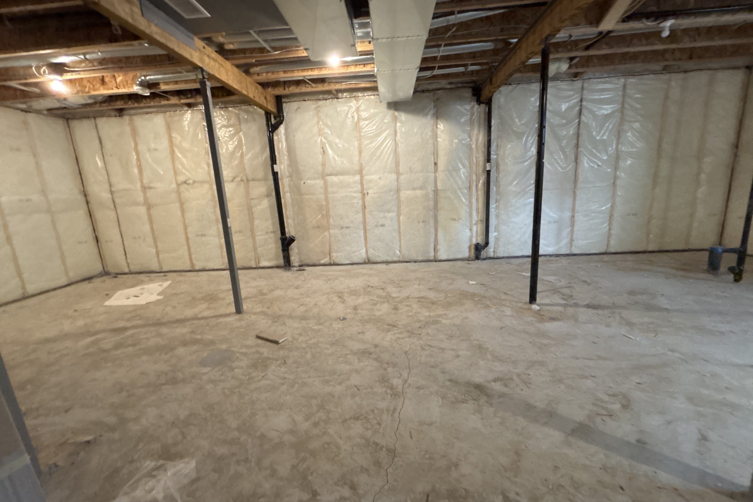Unfinished basement before: steel posts, insulated walls and concrete floor
