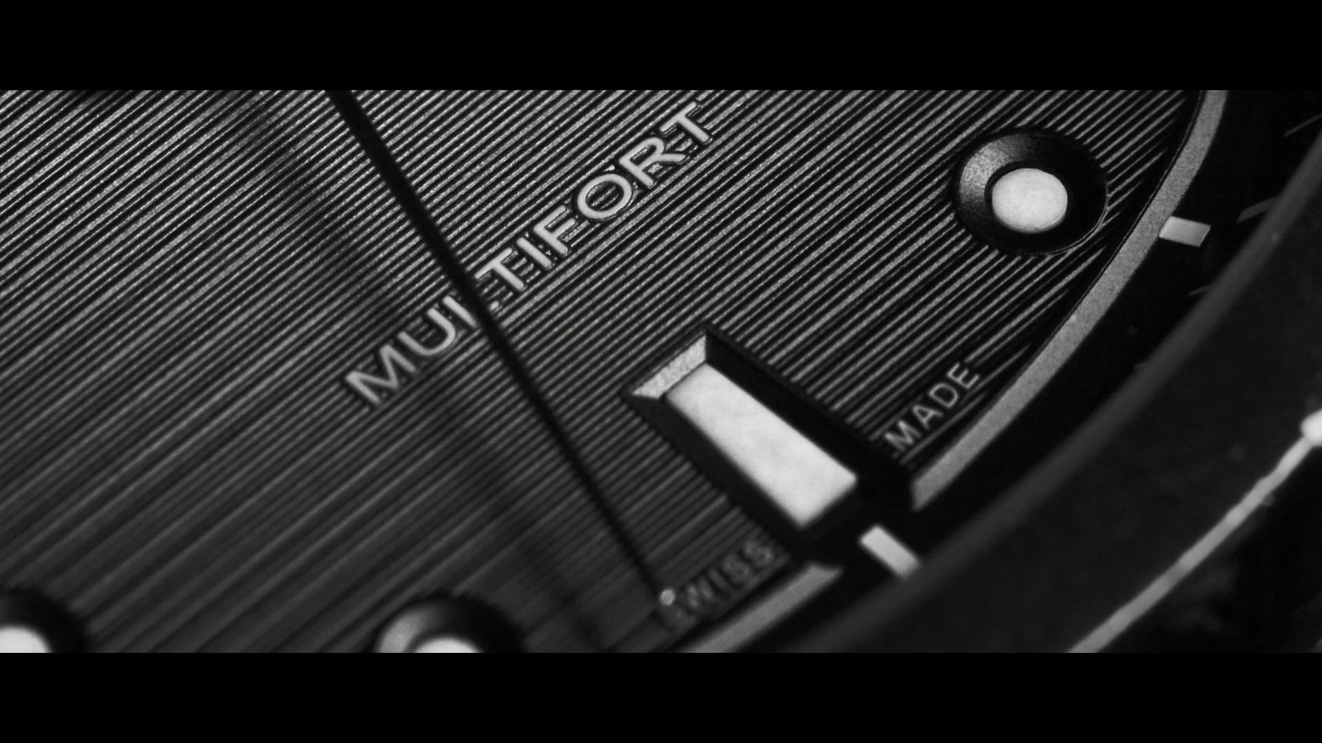 Extreme macro close-up of Mido Multifort TV Big Date watch dial in black and white — spec product commercial cinematography showcasing controlled lighting and detail photography
