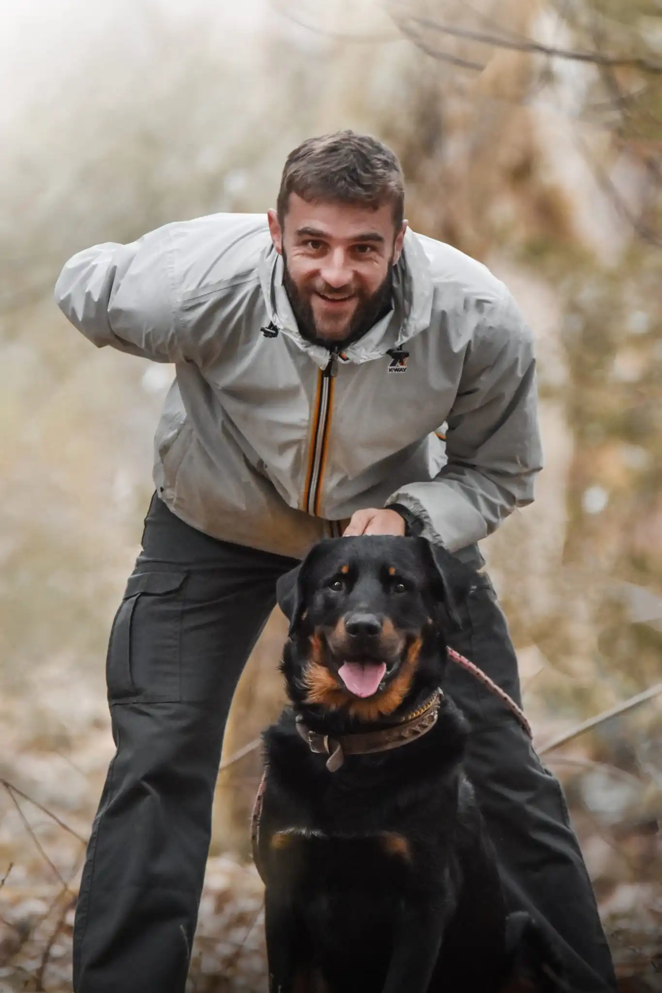 L'educateur canin de Fidel-ac et une jeune beauceron sont de face et sourit a la photo
