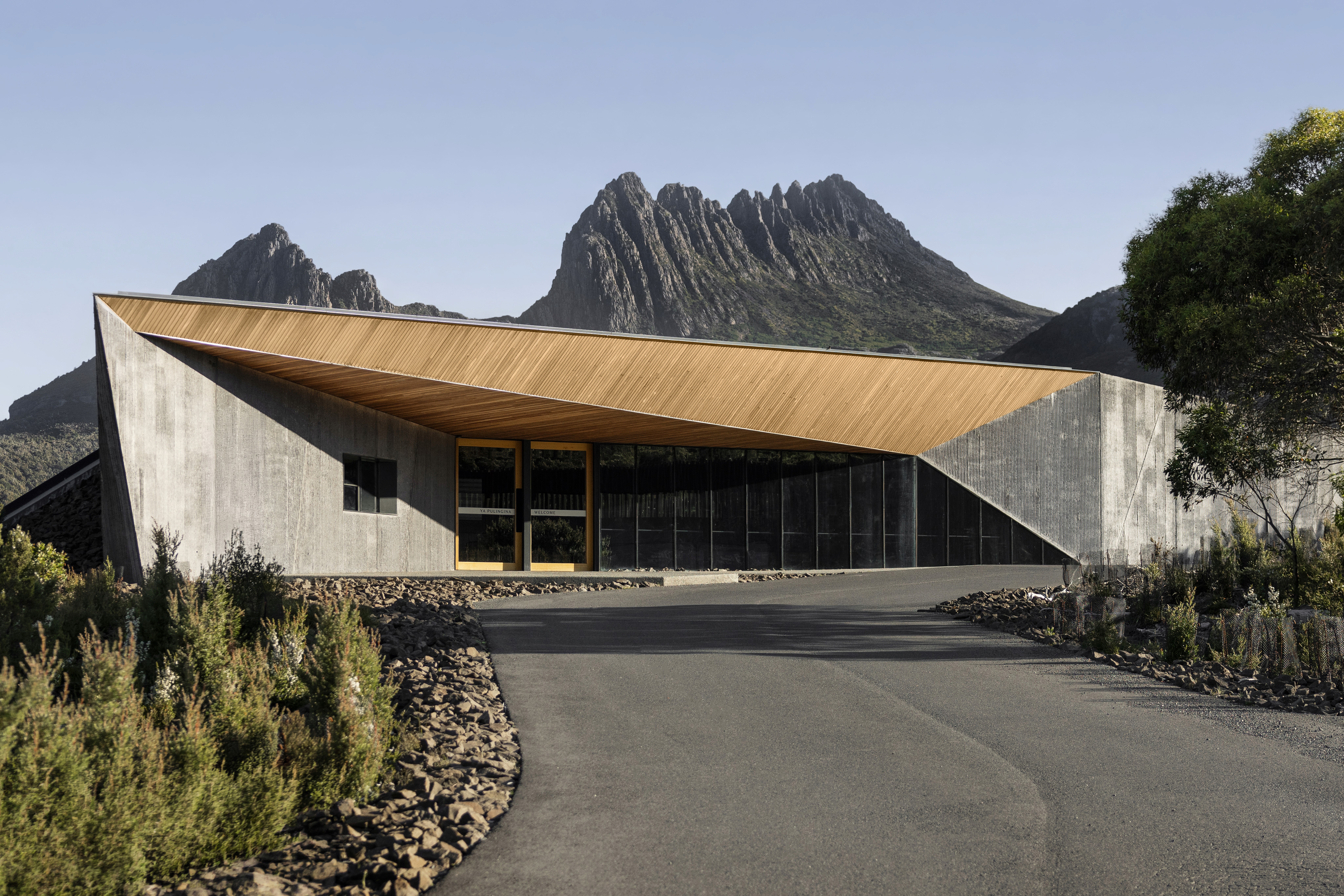 Compositional alignment. The curve of the access path draws the eye toward the structure's sharp geometry, which in turn frames the ancient geology of the park as the true centerpiece.