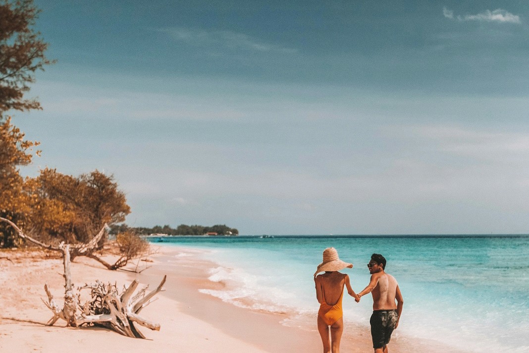 A mood picture two people in swimsuits holding hands walking along a white beach for Imprint’s client Westgate Resorts