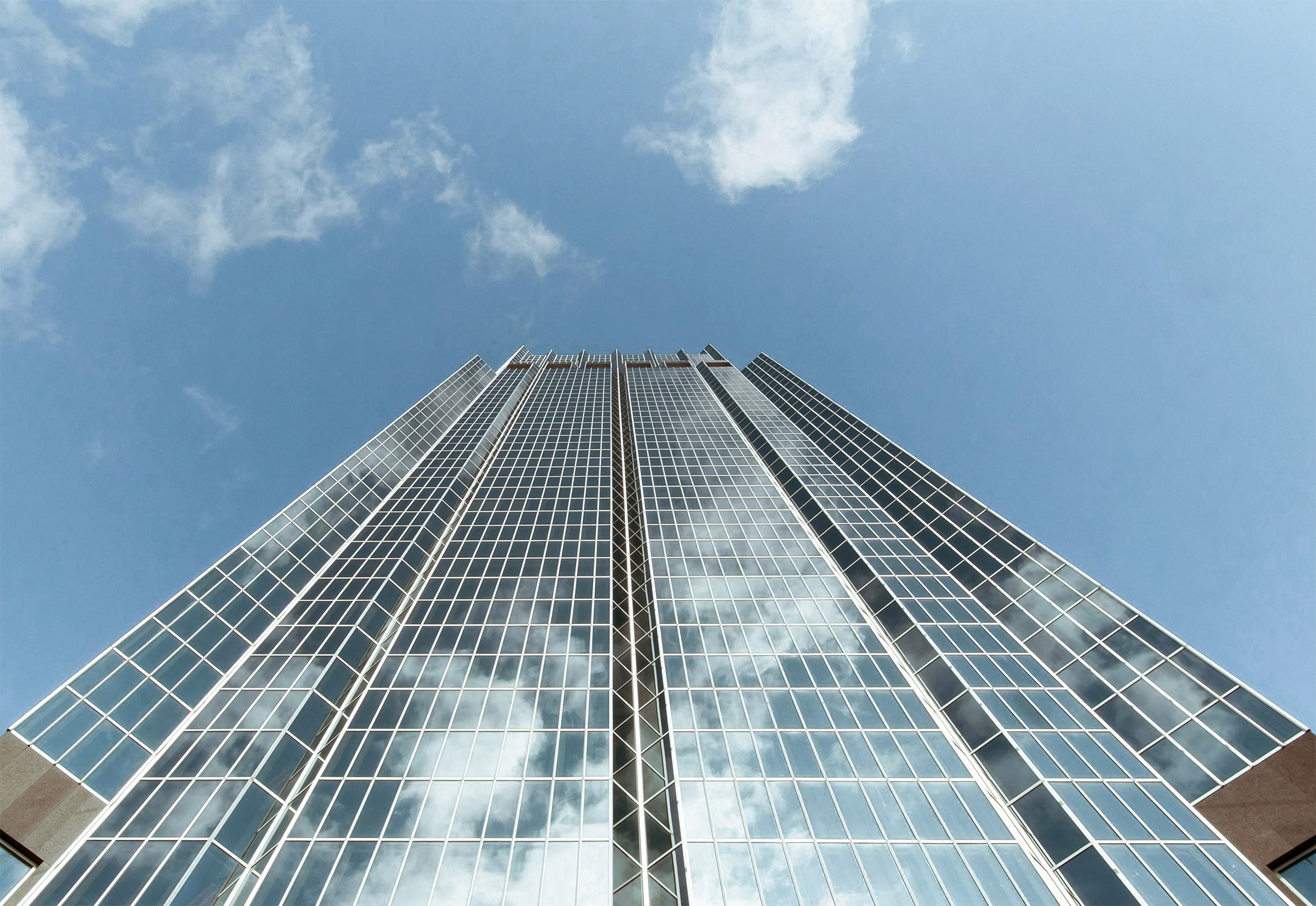 Tall glass skyscraper reaching into a partly cloudy sky.