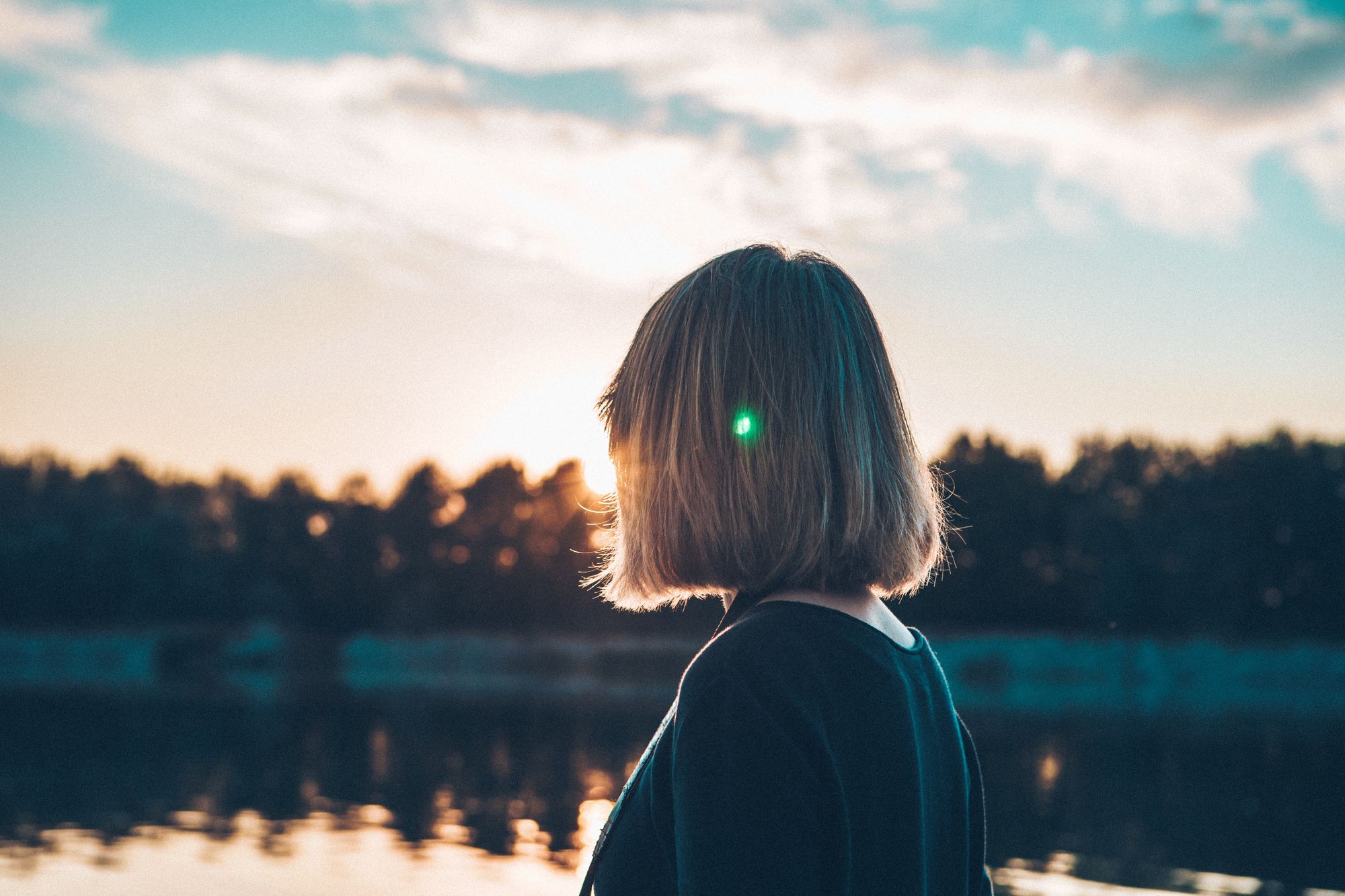 View from behind of blonde female boss looking across the river