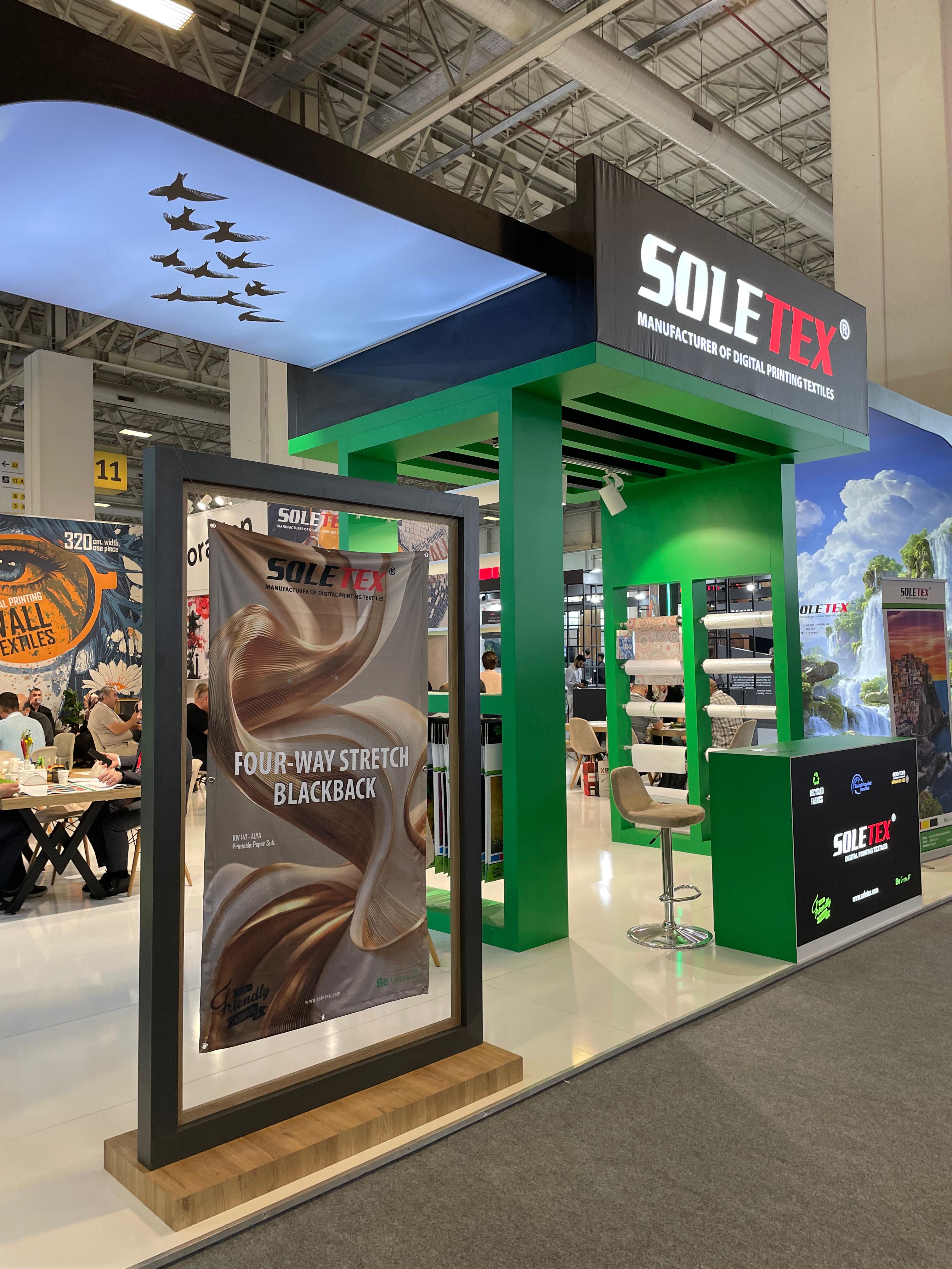 SOLETEX exhibition stand at Sign Istanbul 2026, featuring a large immersive brand environment with bold black and green branding and oversized printed textile graphics.