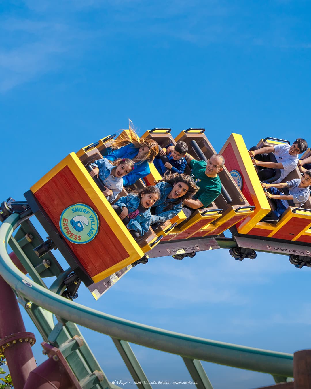 People riding a rollercoaster going in a curl, with children and adults smiling, during things to do in Dubai with family.