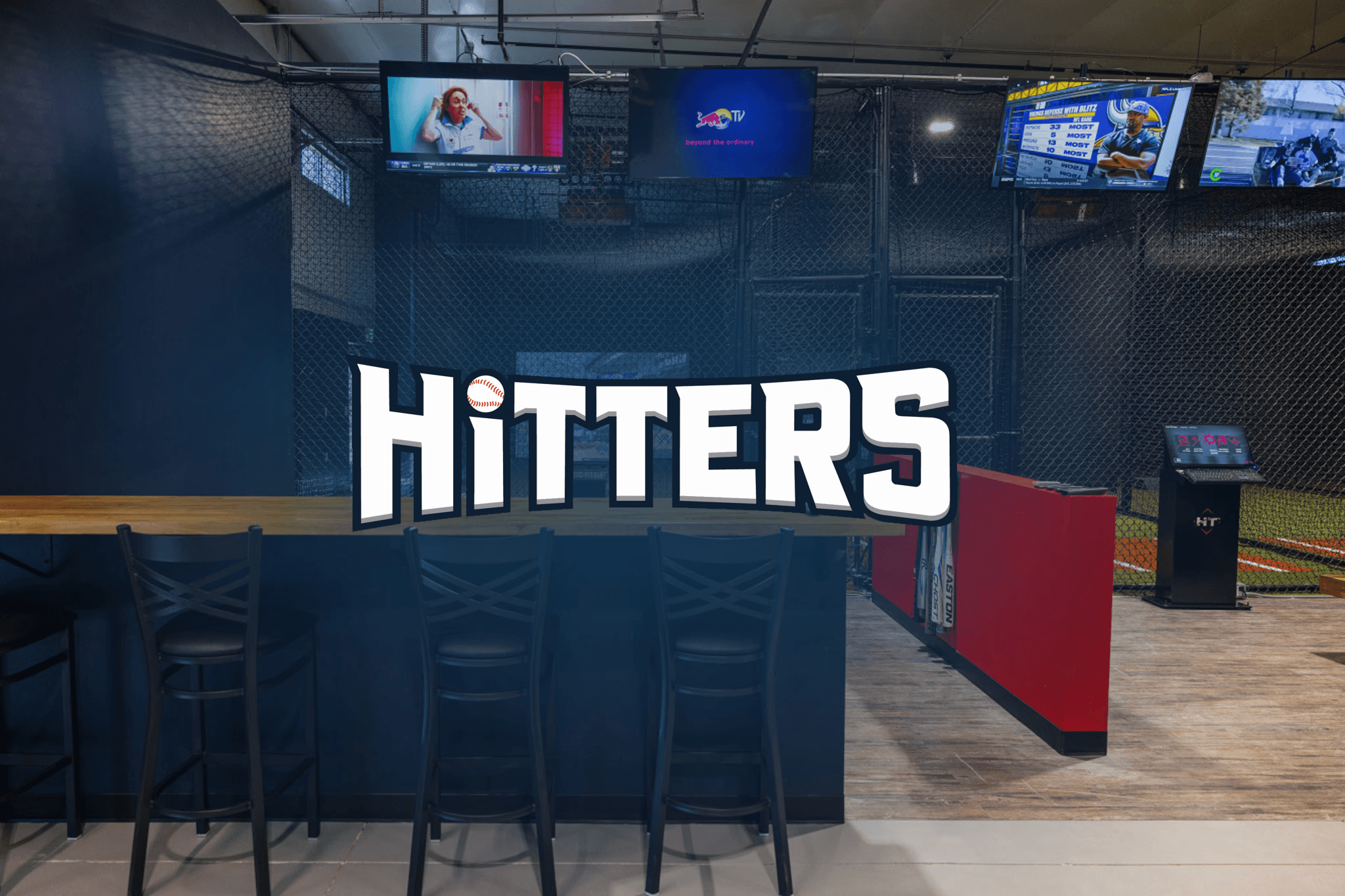 Hitters Liberty Lake logo over a HitTrax Suite batting cage lounge with TVs and seating.