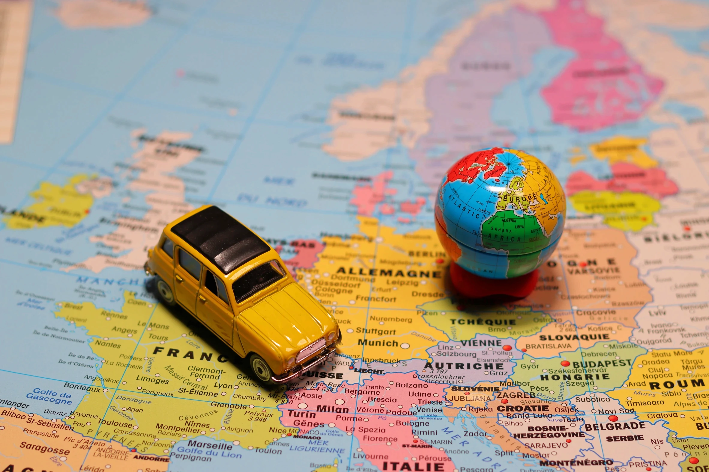 A toy car and miniature globe on a world map
