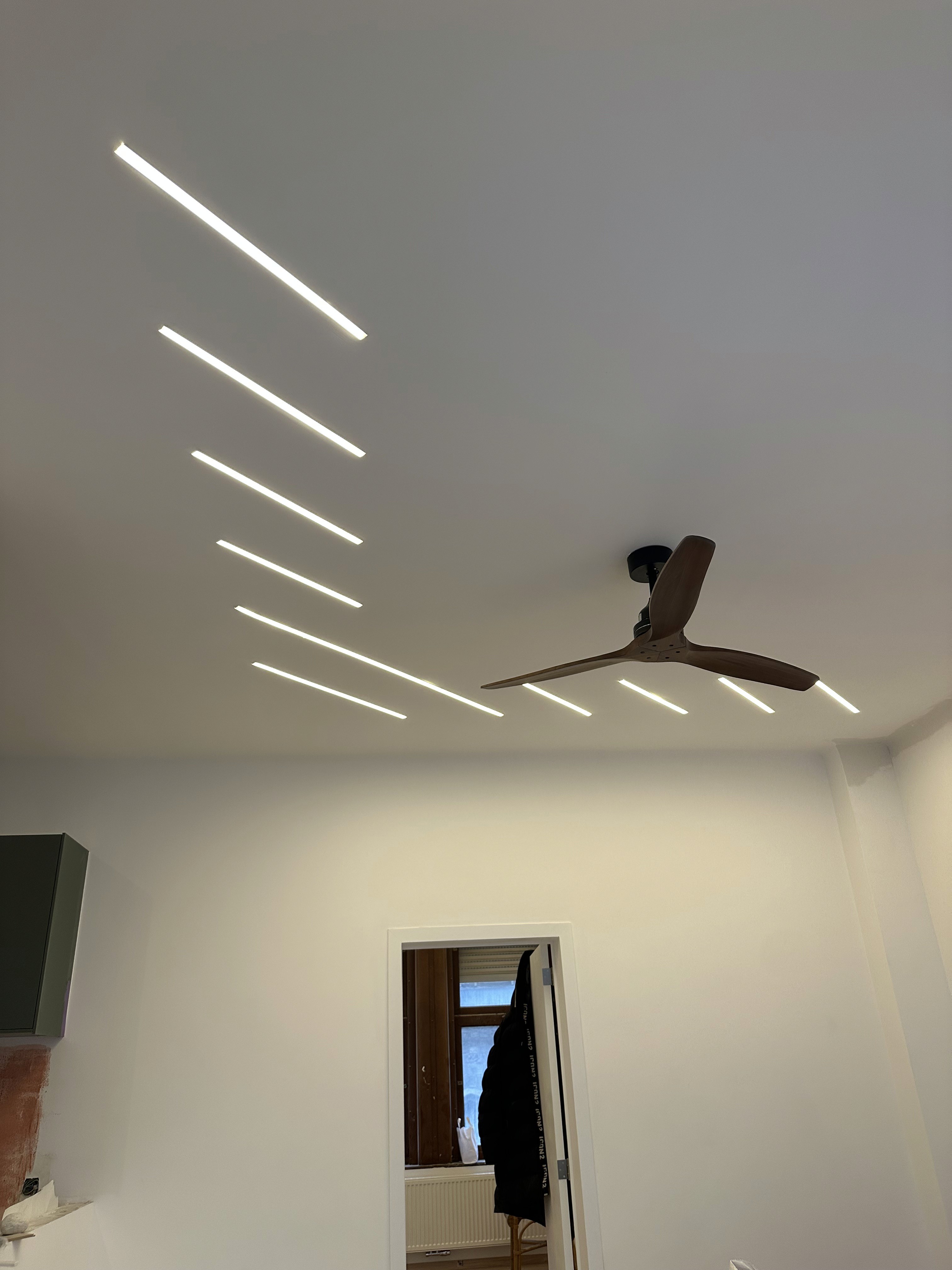 Spacious, luxurious living room with high ceilings, an elegant beige sectional sofa, warm ambient lighting, classical artwork, and rustic architectural elements, featuring an open layout with a view of a mezzanine level.