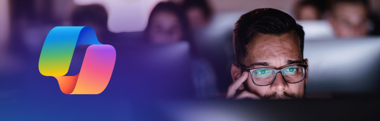 Ein Mann mit Brille, der konzentriert vor einem Computerbildschirm arbeitet, mit verschwommenen Figuren im Hintergrund. Links ist ein buntes Logo mit einem stilisierten Design zu sehen.