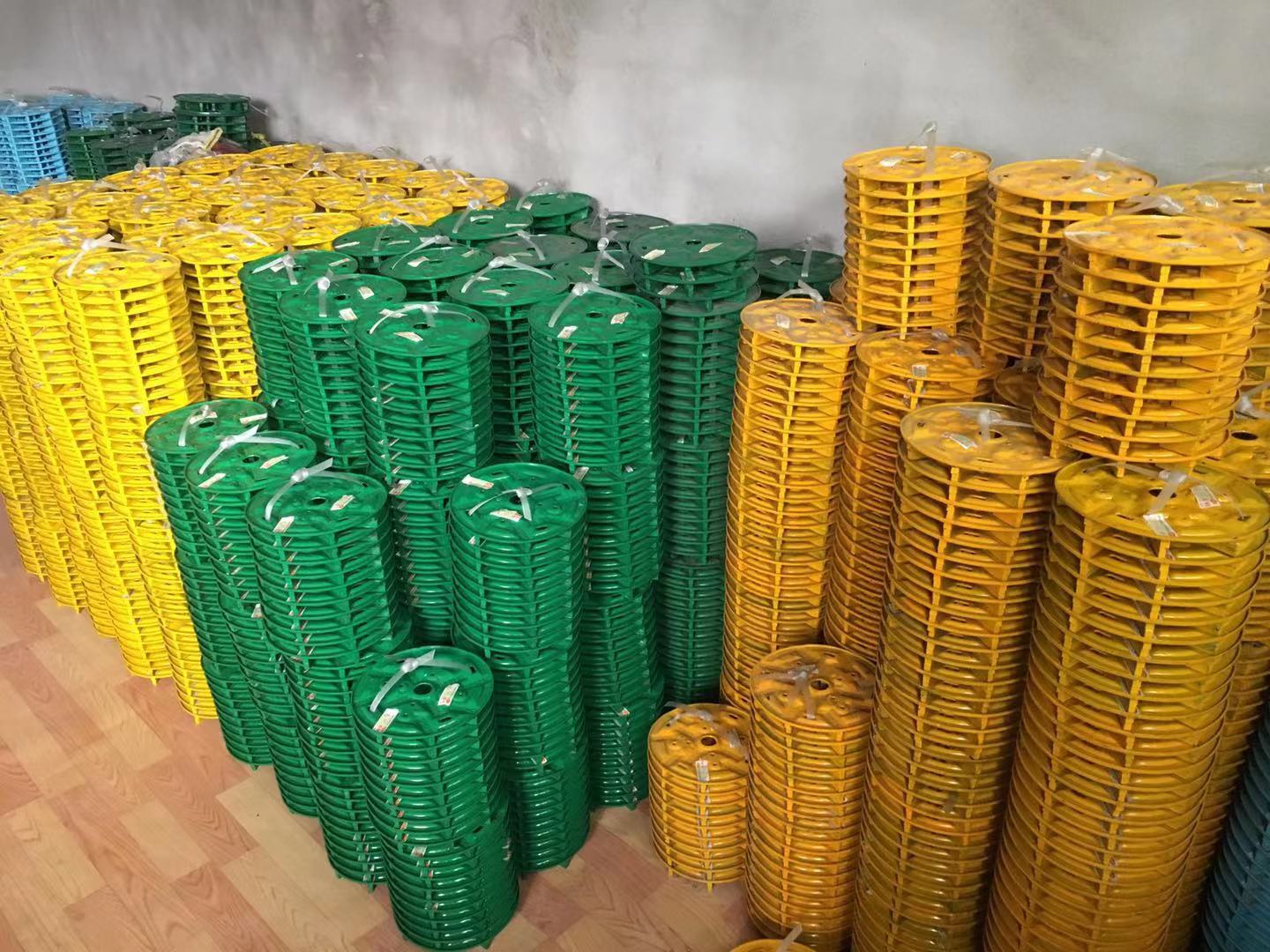 Stacks of green, yellow, and blue Metal/Resin Bond Grinding Discs in a warehouse.