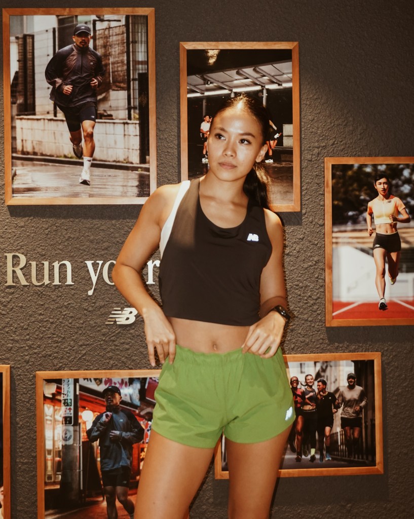A female runner posing confidently in activewear against a backdrop of framed running photographs, emphasizing the theme of community in sports.