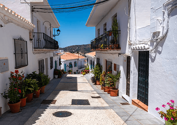 Whitewashed village street with cobblestones and colorful flowers in Andalusia