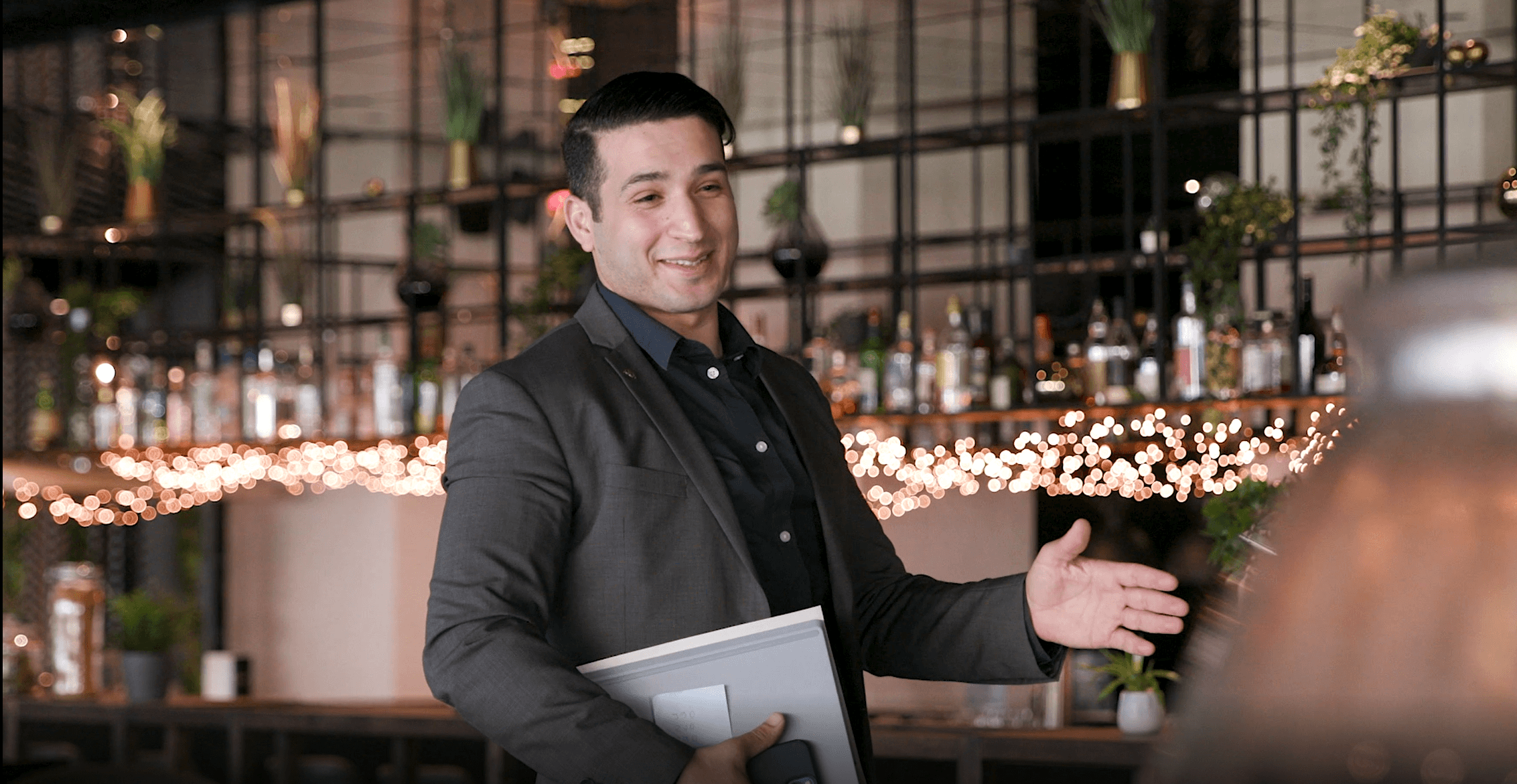A man in a suit hands a card to a woman at a modern reception desk with a textured background.
