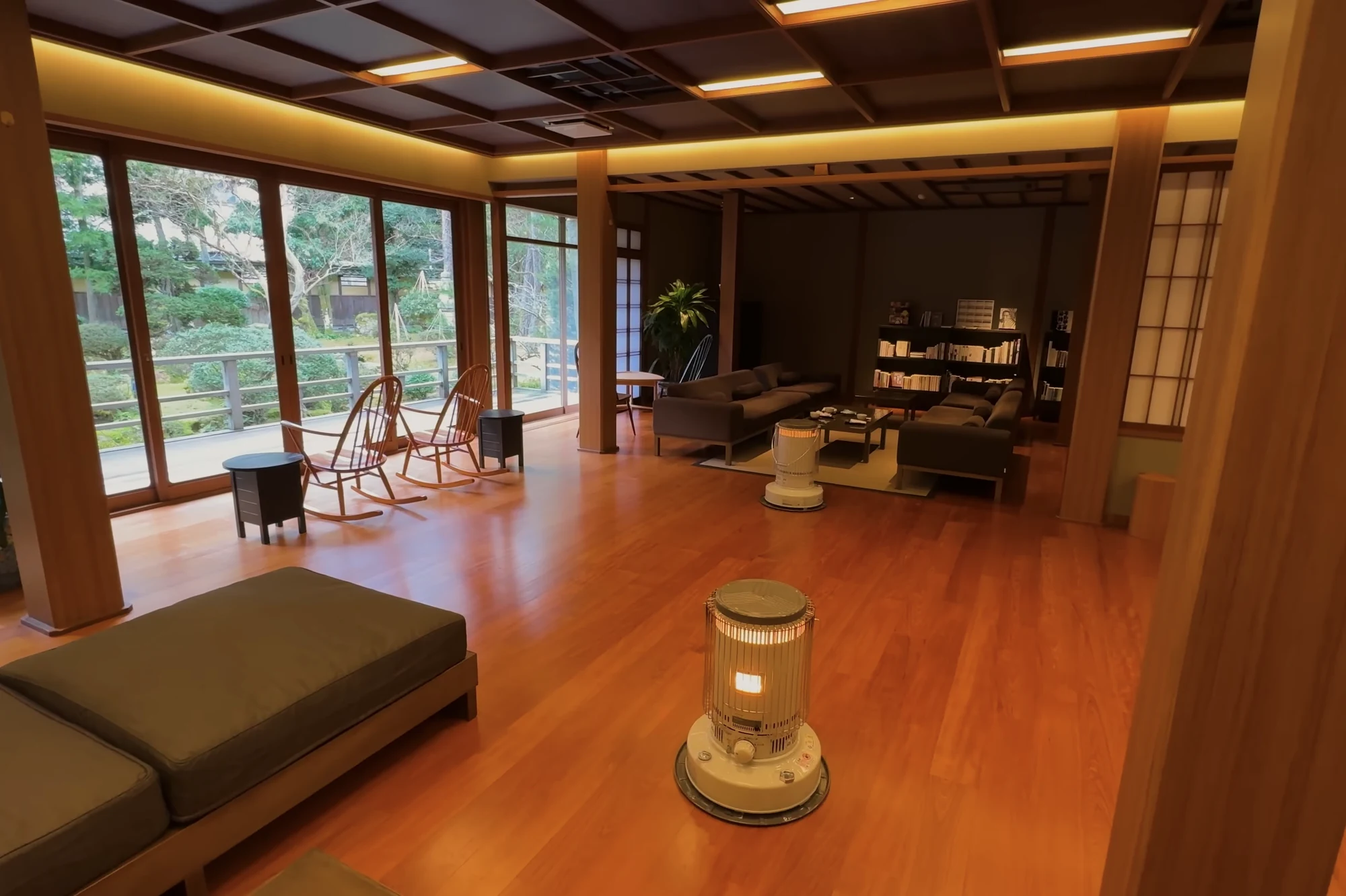 A ryokan lounge in Kinosaki with low seating, timber floors and a garden filling the window.