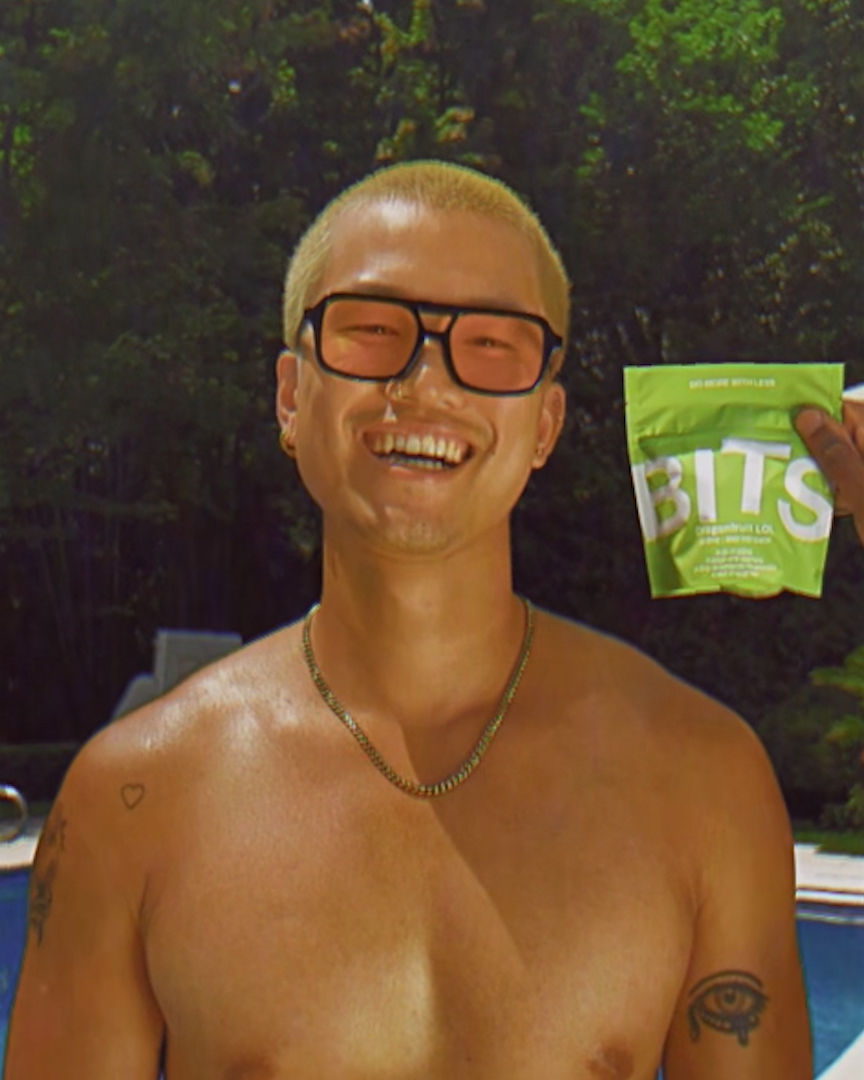 A tan sighthound stands in a grassy field.